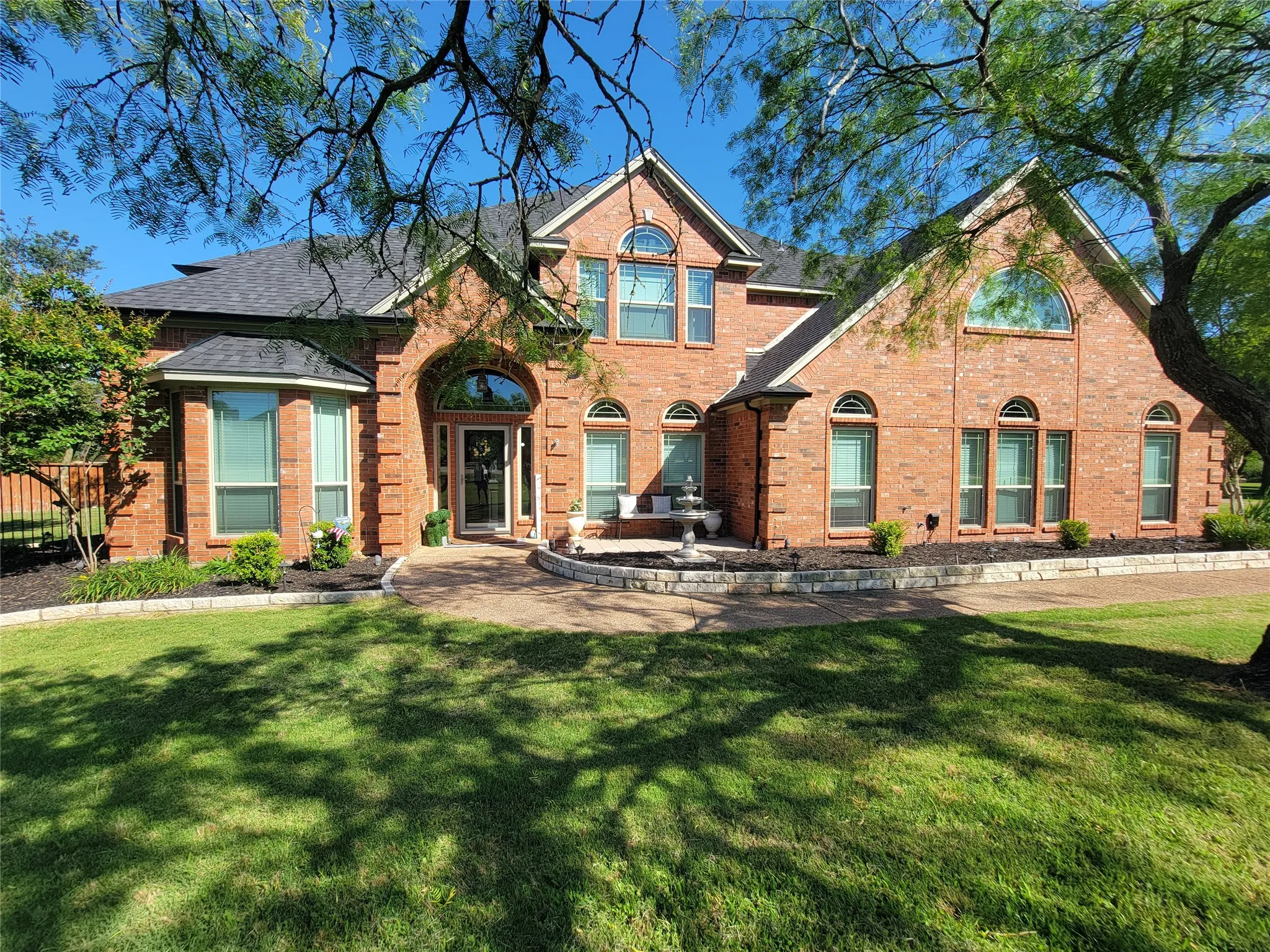 Red brick facade featuring multiple arched windows, an arched entry, and a multi-level roofline