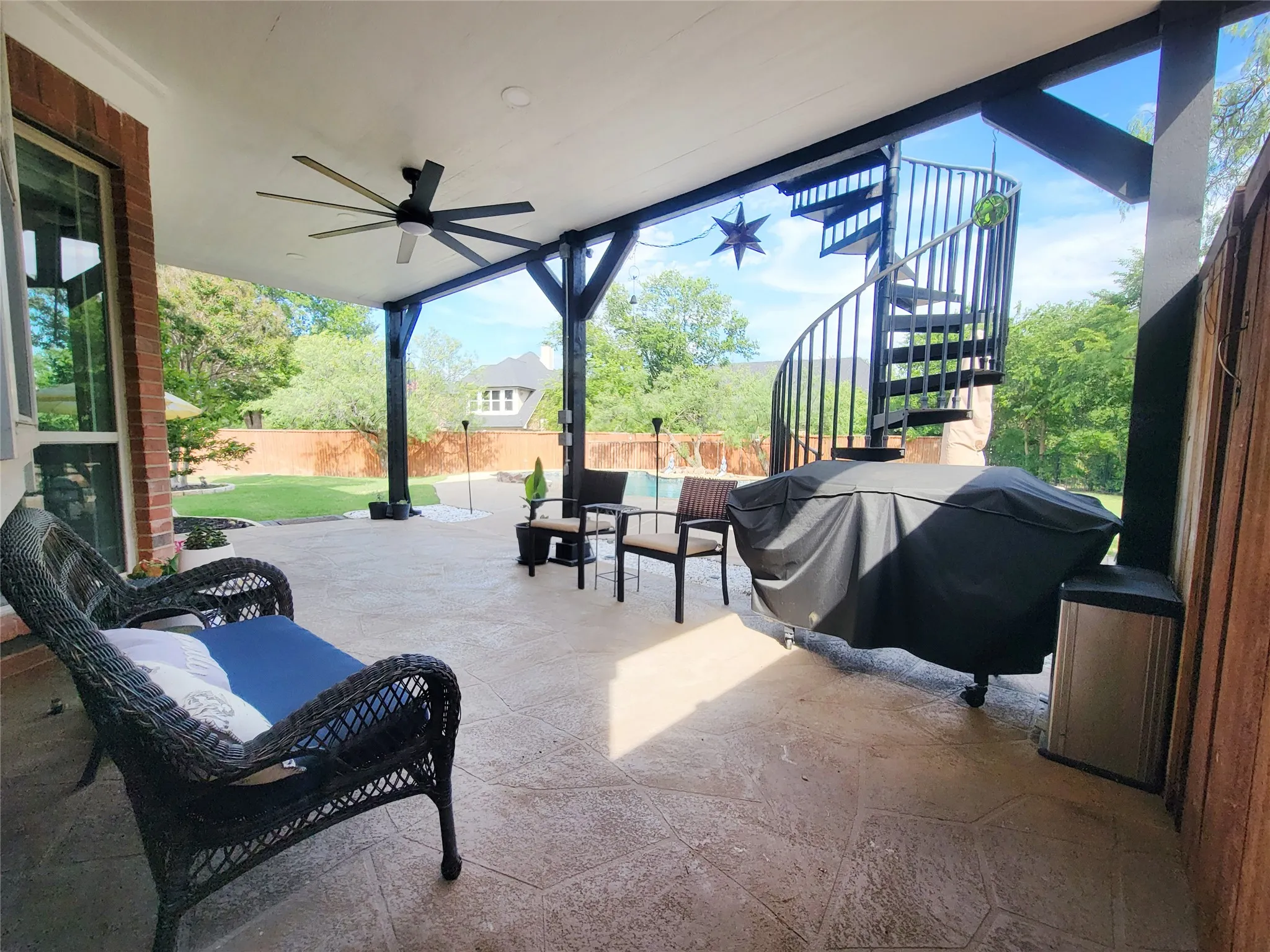 Expansive covered patio featuring a stamped concrete floor, a ceiling fan, and exposed beam ceiling