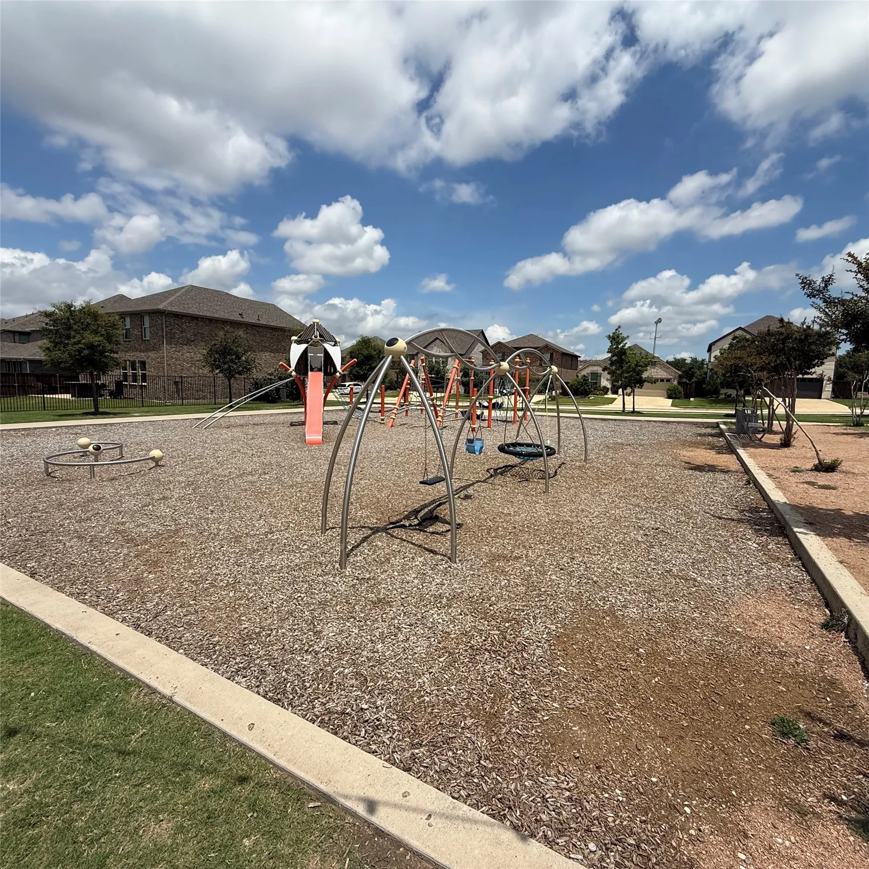 Community playground featuring multiple swings, a slide structure, and a circular spinner