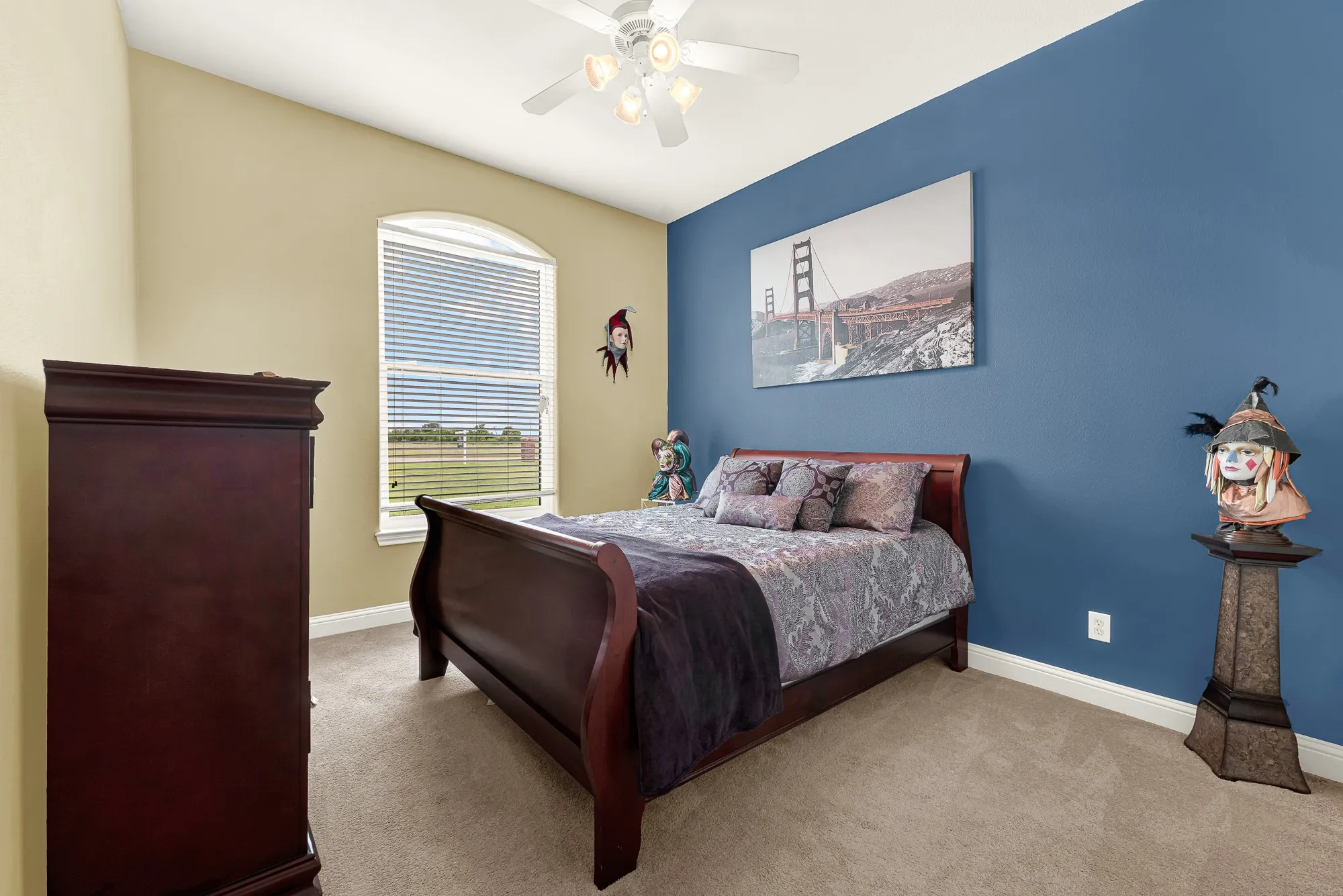 3rd private bedroom location carpeted interior space featuring a single arched window with blinds, ceiling fan with light fixture, and contrasting wall colors