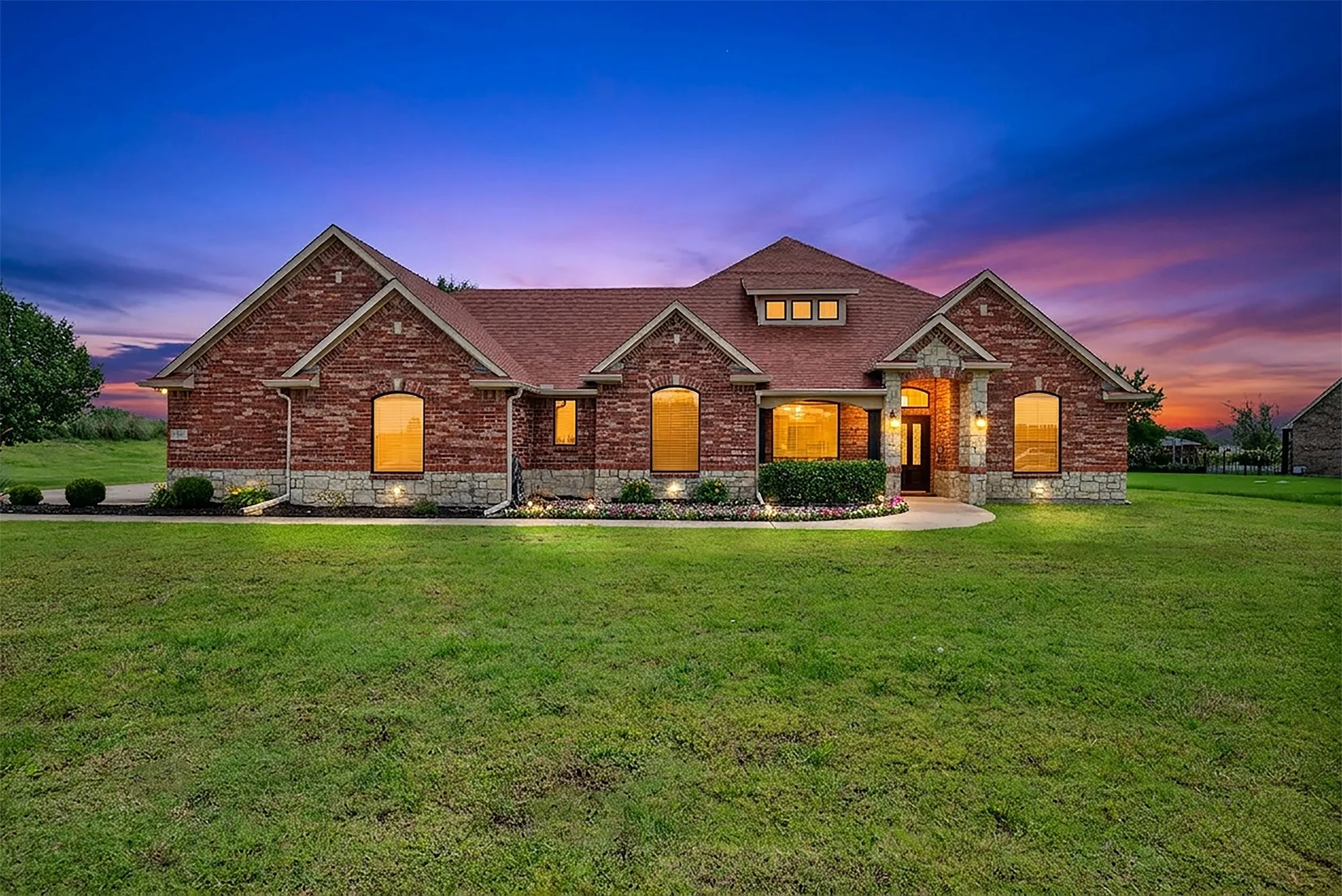 Brick and stone exterior featuring an arched entryway, gabled rooflines, and multiple windows