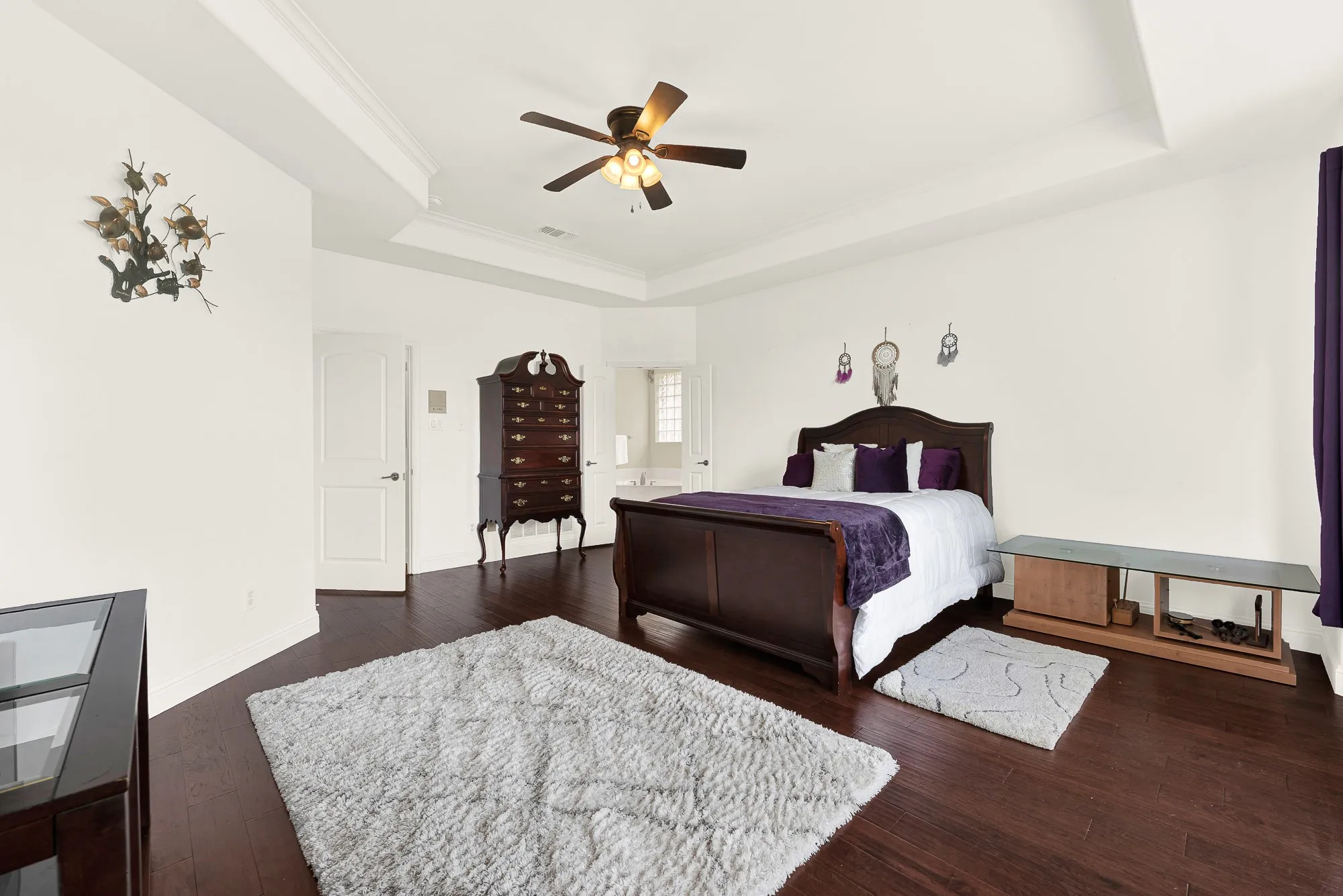 Lake-view, Spacious room featuring rich wood-finish flooring, a tray ceiling, and a ceiling fan with integrated lighting