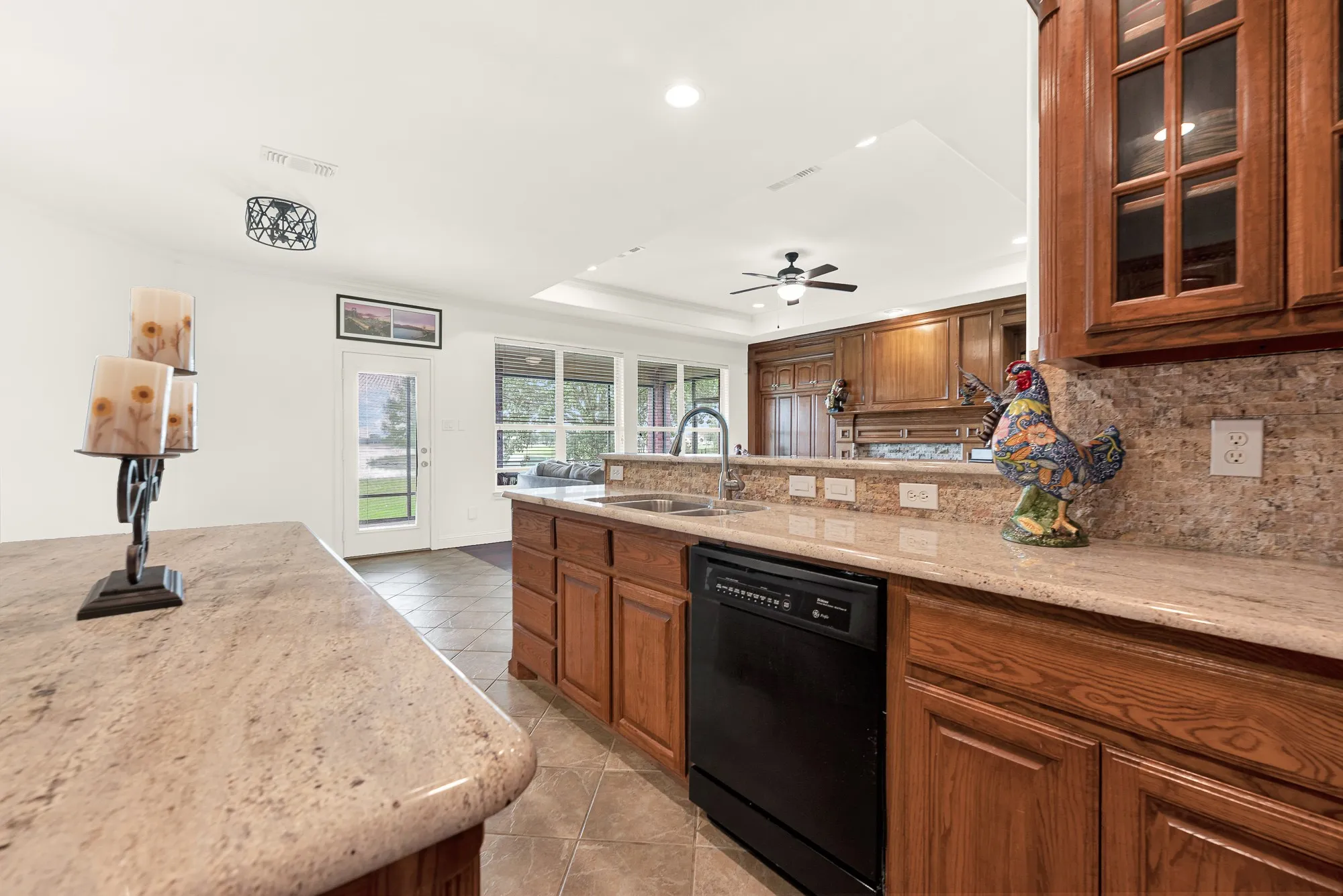 Spacious kitchen featuring granite countertops, wood cabinetry, a tile backsplash, and integrated appliances