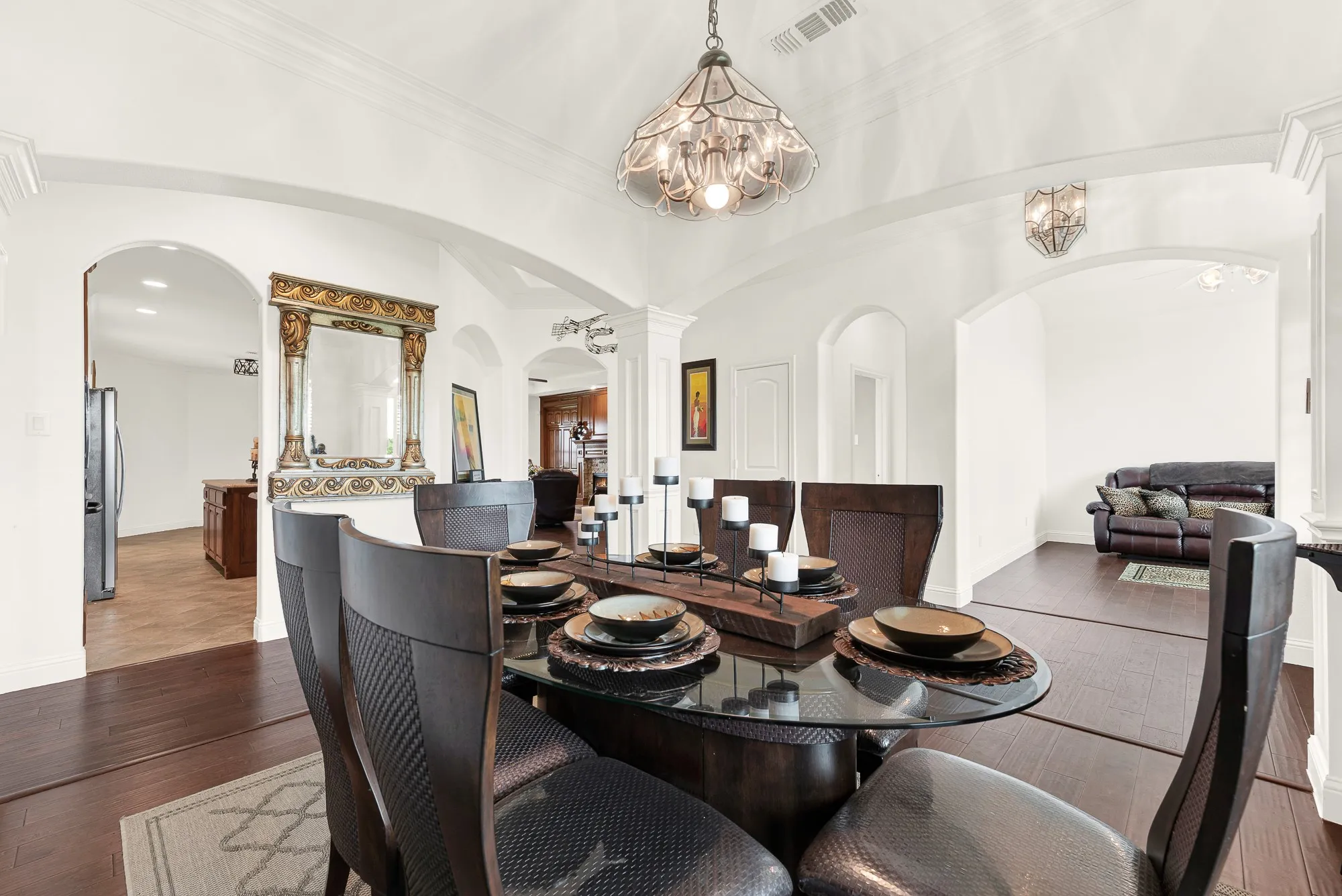 Dining area featuring a vaulted ceiling with an ornate chandelier, archway entries, crown molding, and wood-finish flooring