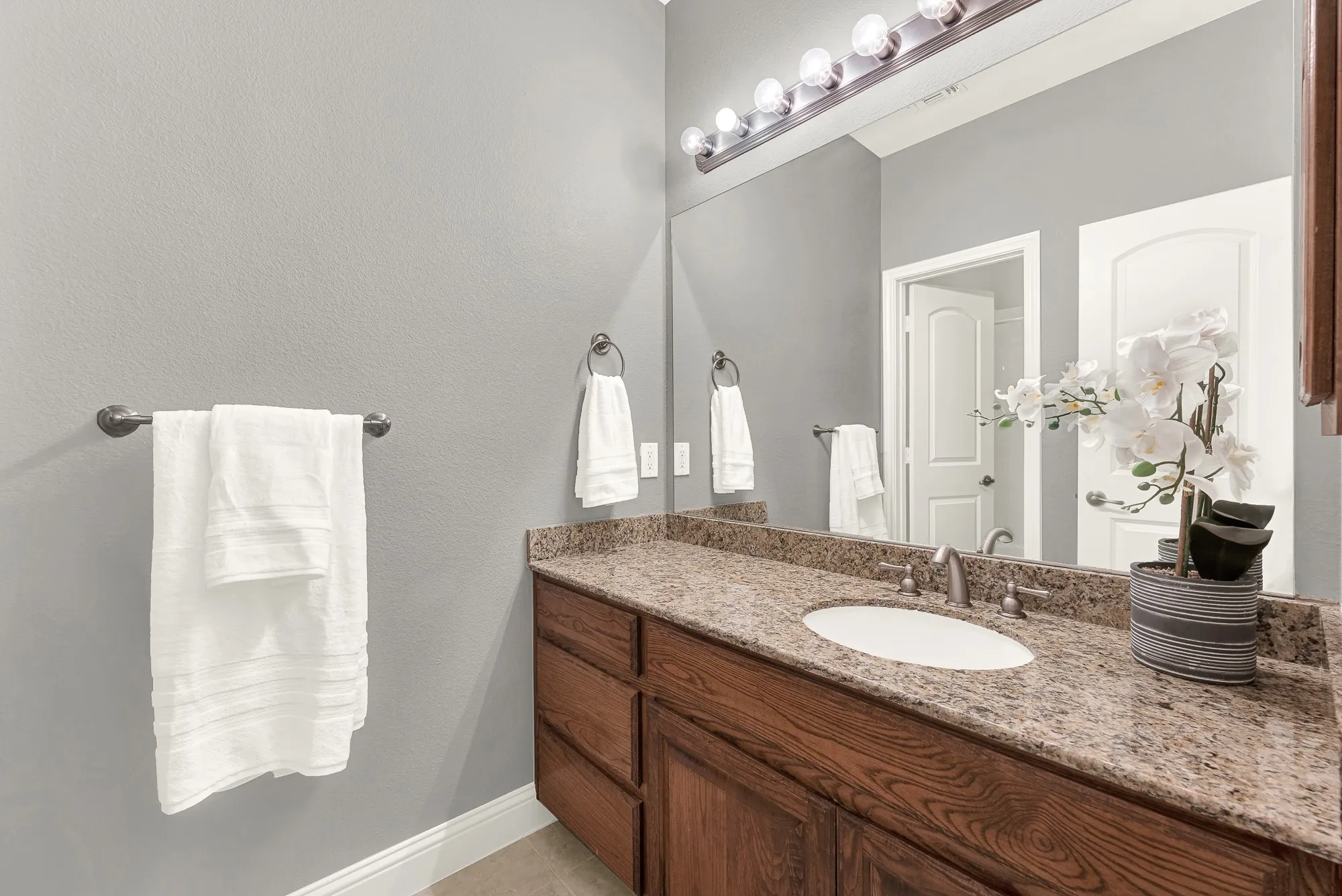Vanity featuring wood-finish cabinetry, a white oval undermount sink, and a speckled countertop