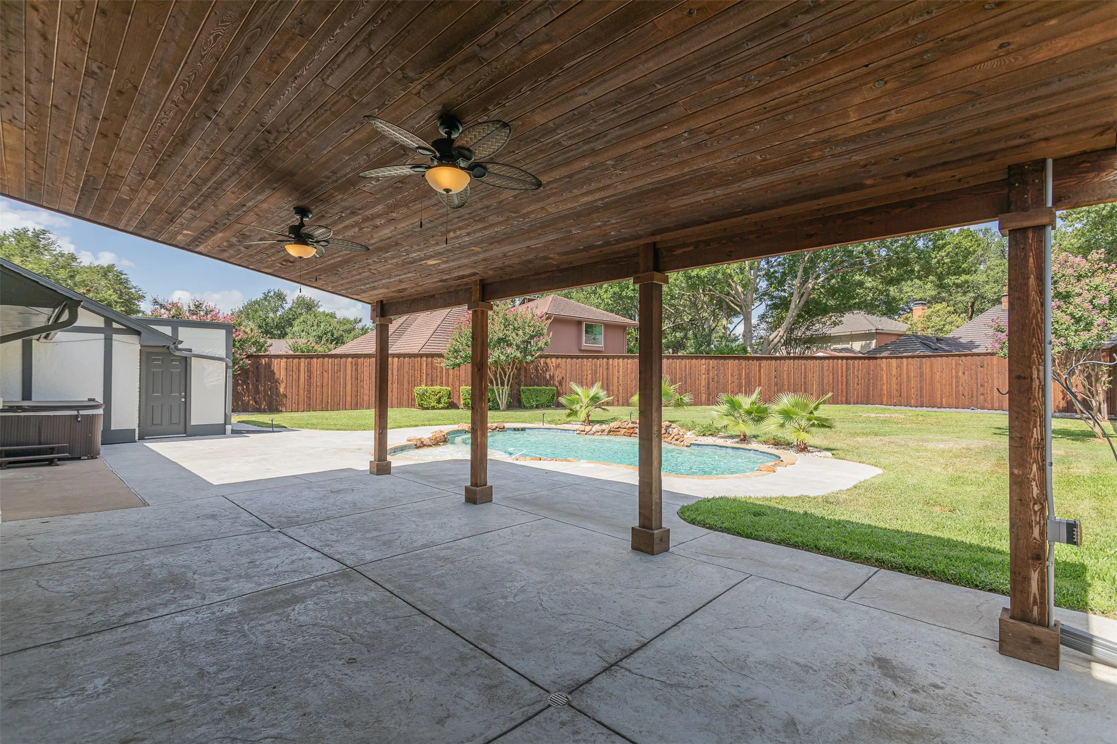 Covered outdoor living space complete with ceiling fan and room for grilling or outdoor lounging.
