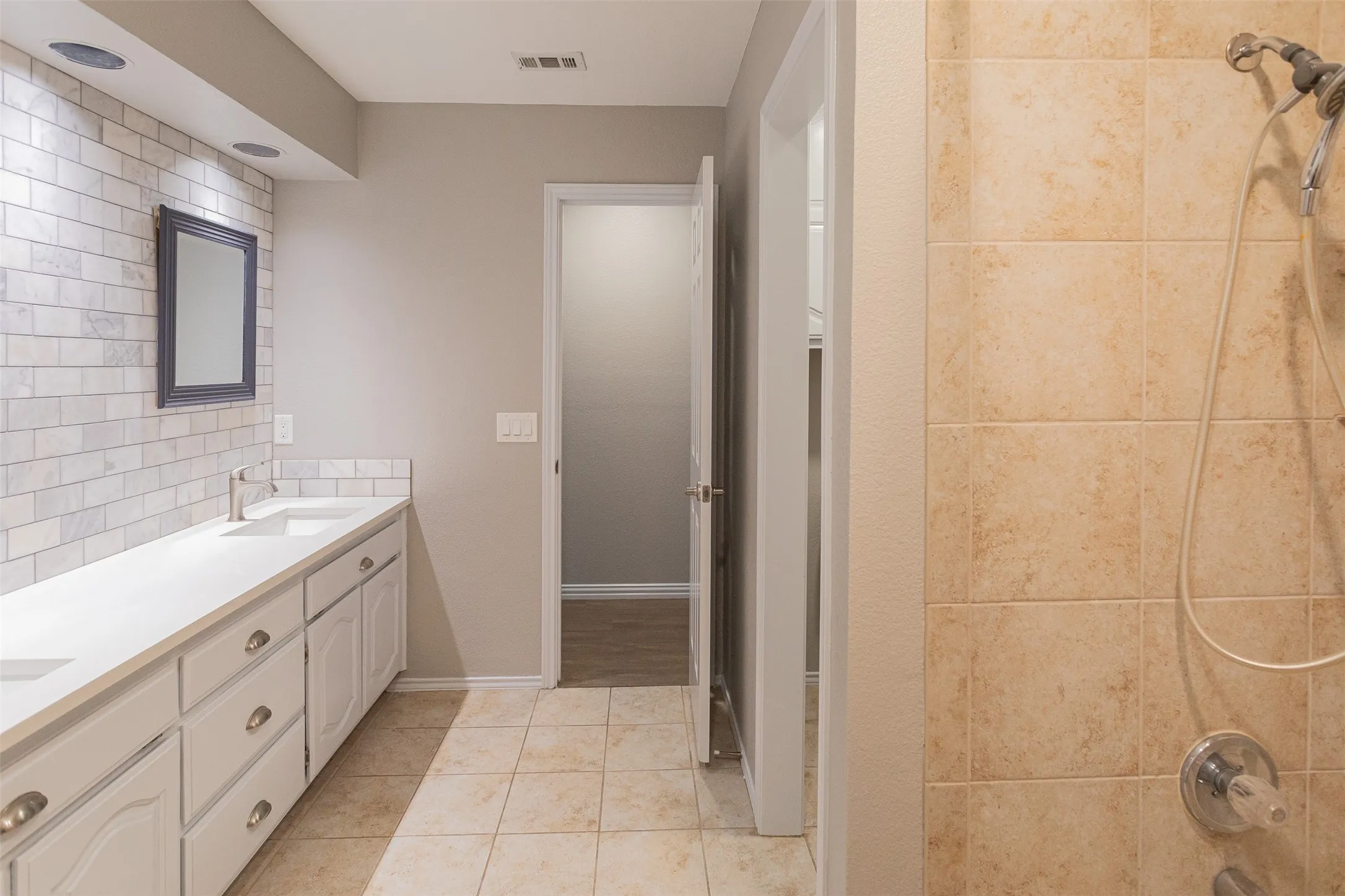 Thoughtfully designed secondary bathroom featuring dual vanities, ample storage, and a tub/shower combination.