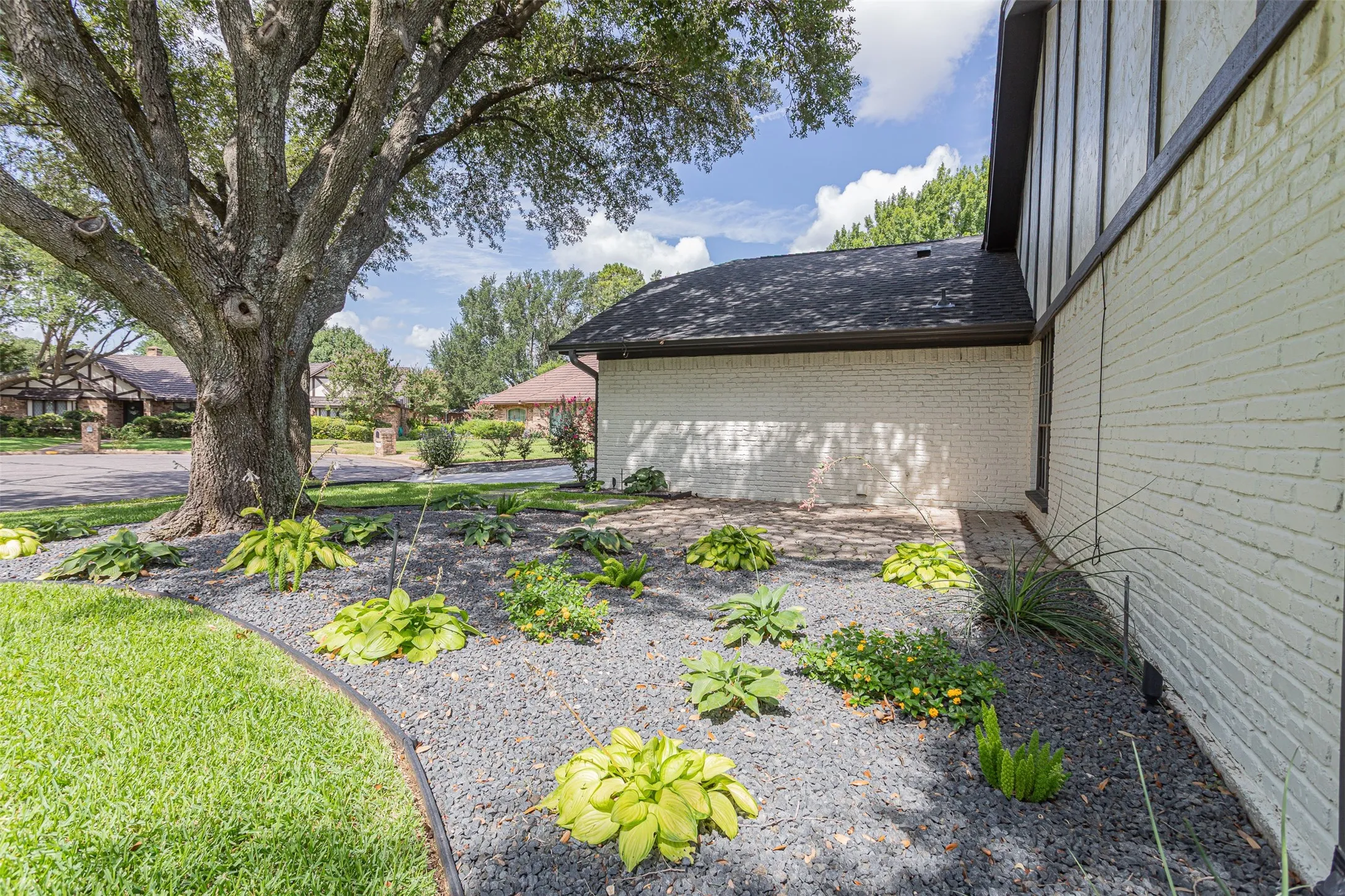 Inviting front courtyard featuring lush landscaping and a cozy sitting area.