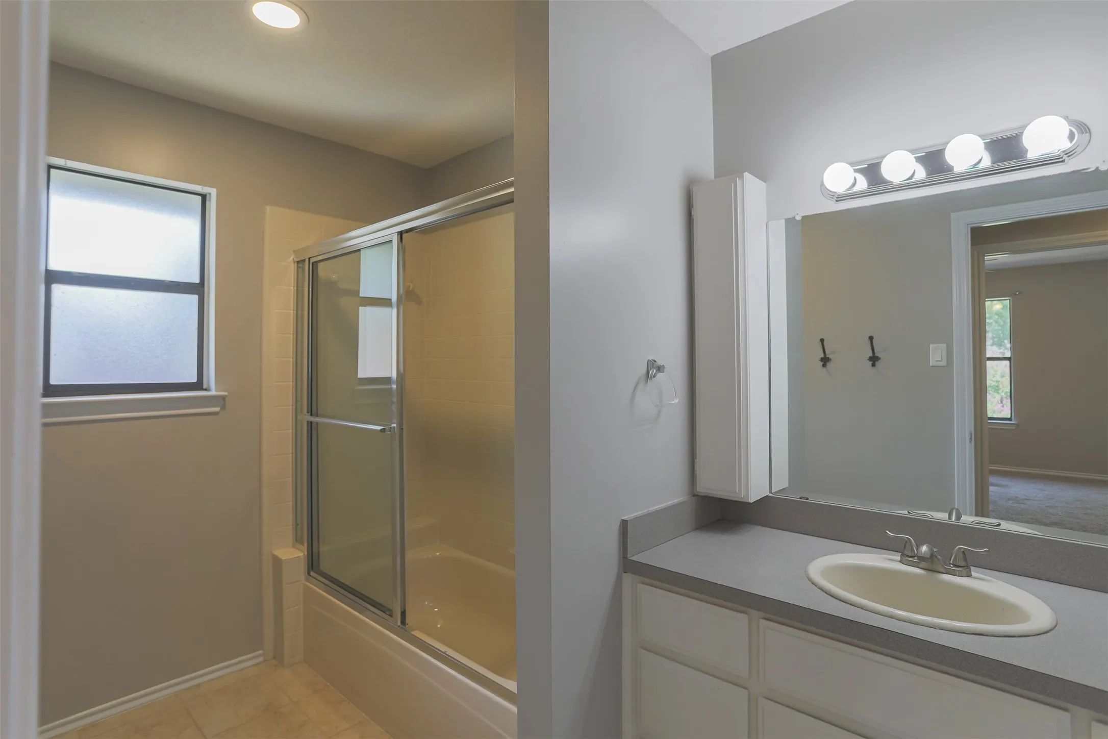 Convenient upstairs full bath with a sliding glass shower and functional vanity.
