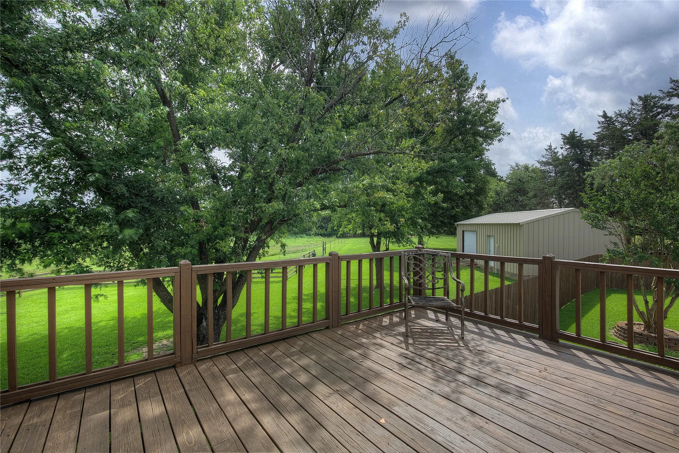 This deck on the second floor is accessible through the primary suite. It overlooks the back yard/pool and the adjoining acreage