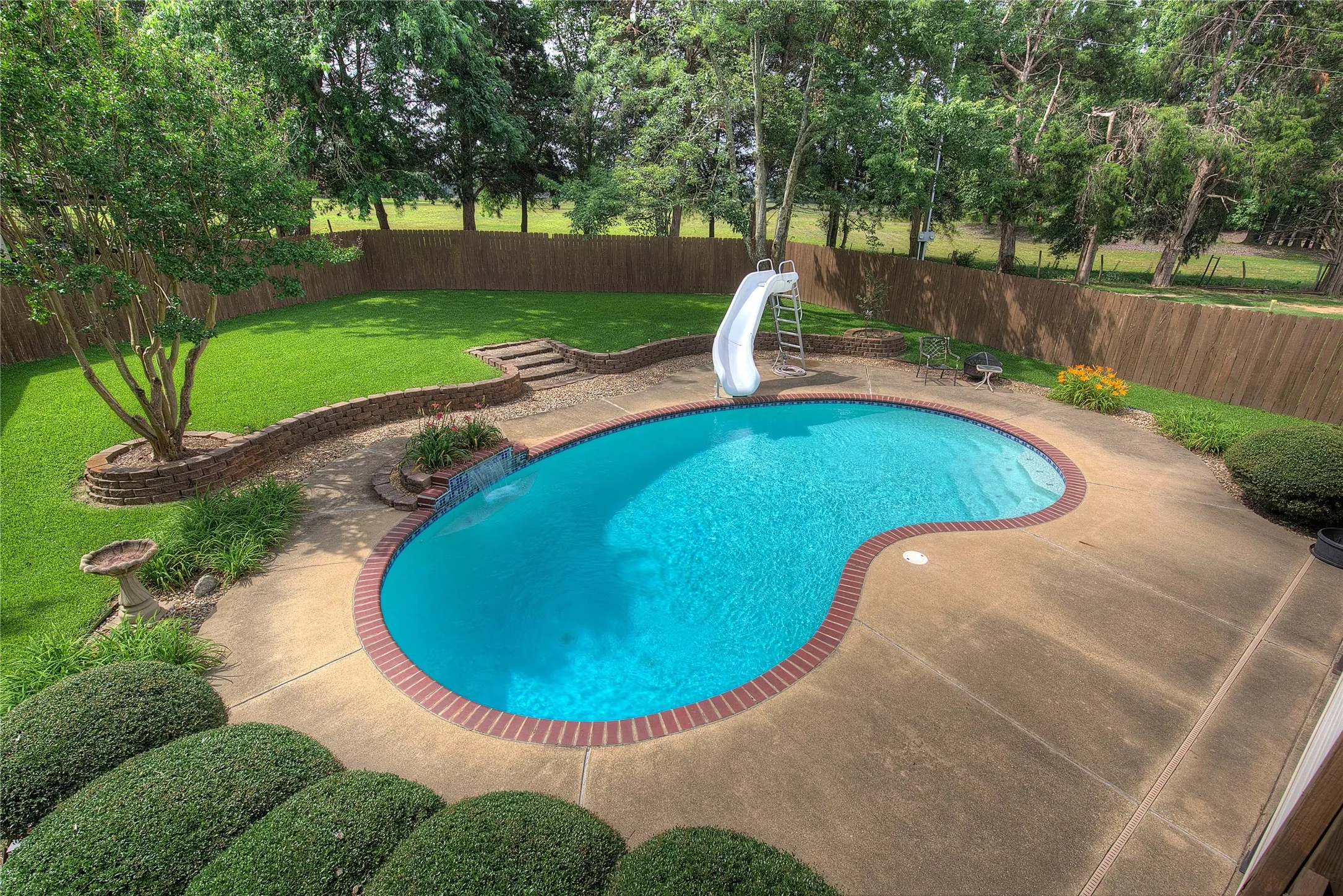 Gorgeous in-ground pool with waterfall and slide, plus manicured St. Augustine lawn and privacy fence