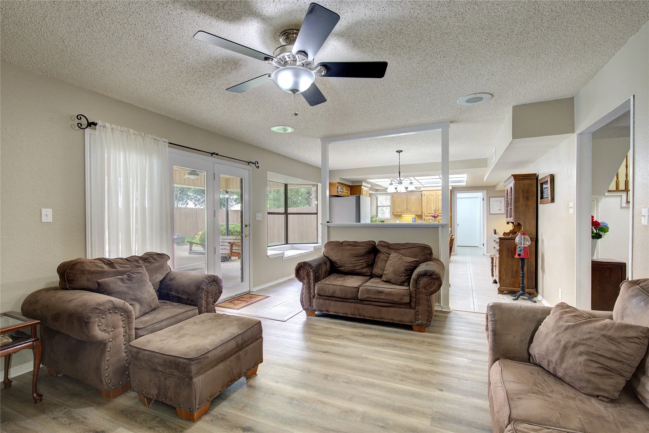Living room is open to kitchen/breakfast area, with glass doors to the back porch and pool area.