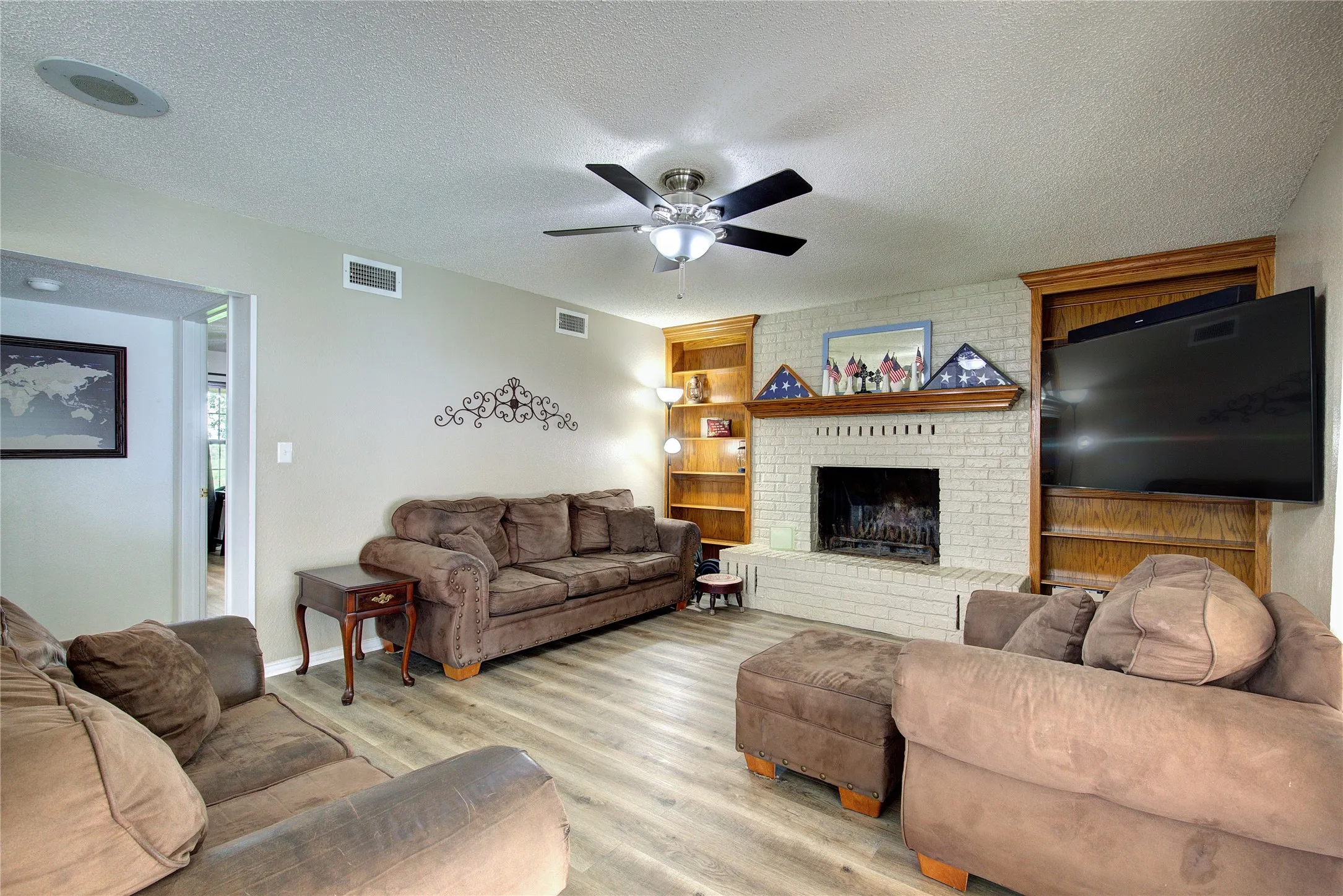 Living room is spacious, with a full-height brick hearth surrounding a wood-burning fireplace.