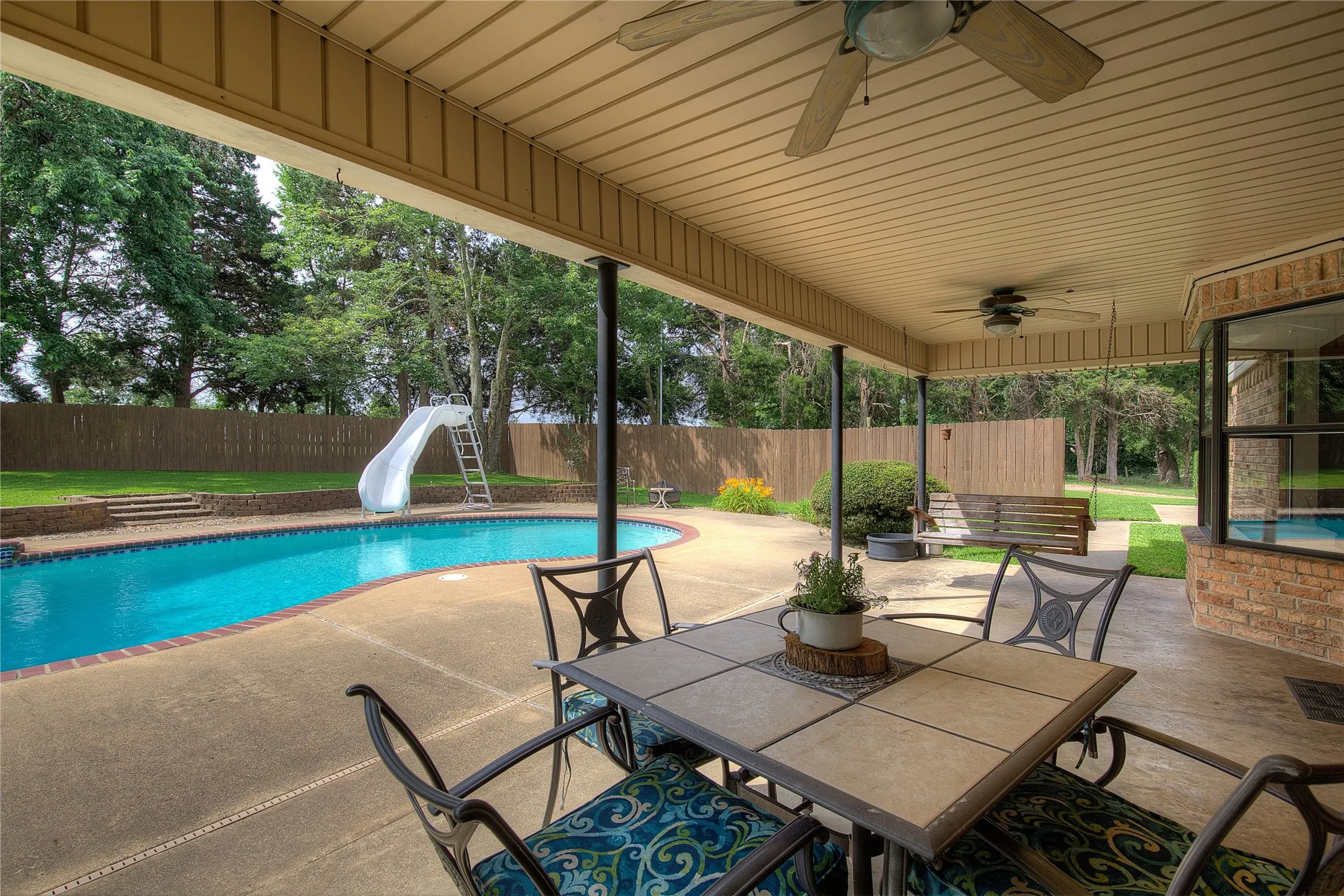 The covered back porch has plenty of room for outdoor dining, plus concrete decking around a 32x16 gunite pool with slide and waterfall!