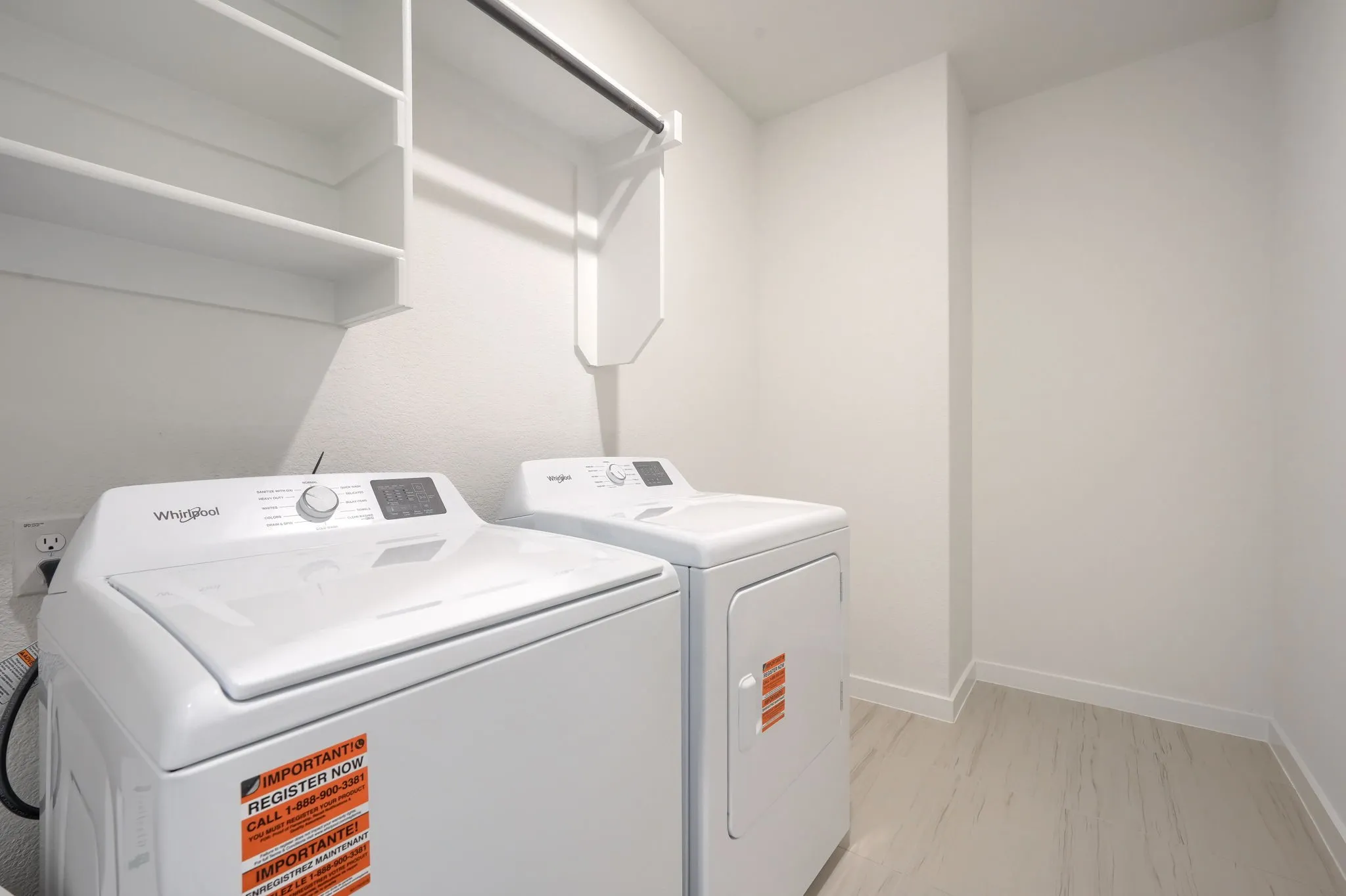 Dedicated laundry area featuring a built-in shelving unit, overhead clothes rod, and light wood-finish flooring