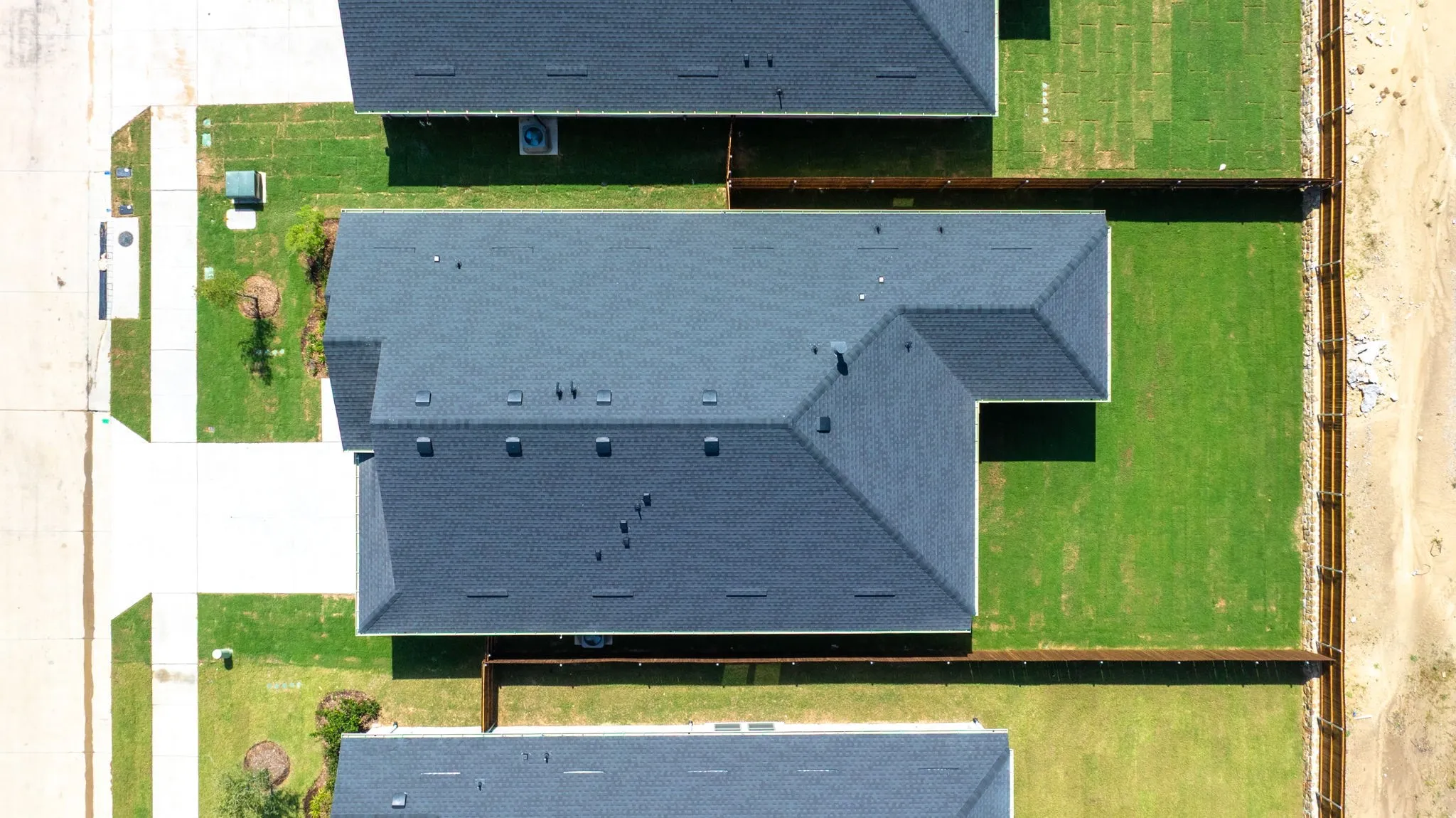 New construction residence featuring a dark shingle roof and a spacious, manicured lawn