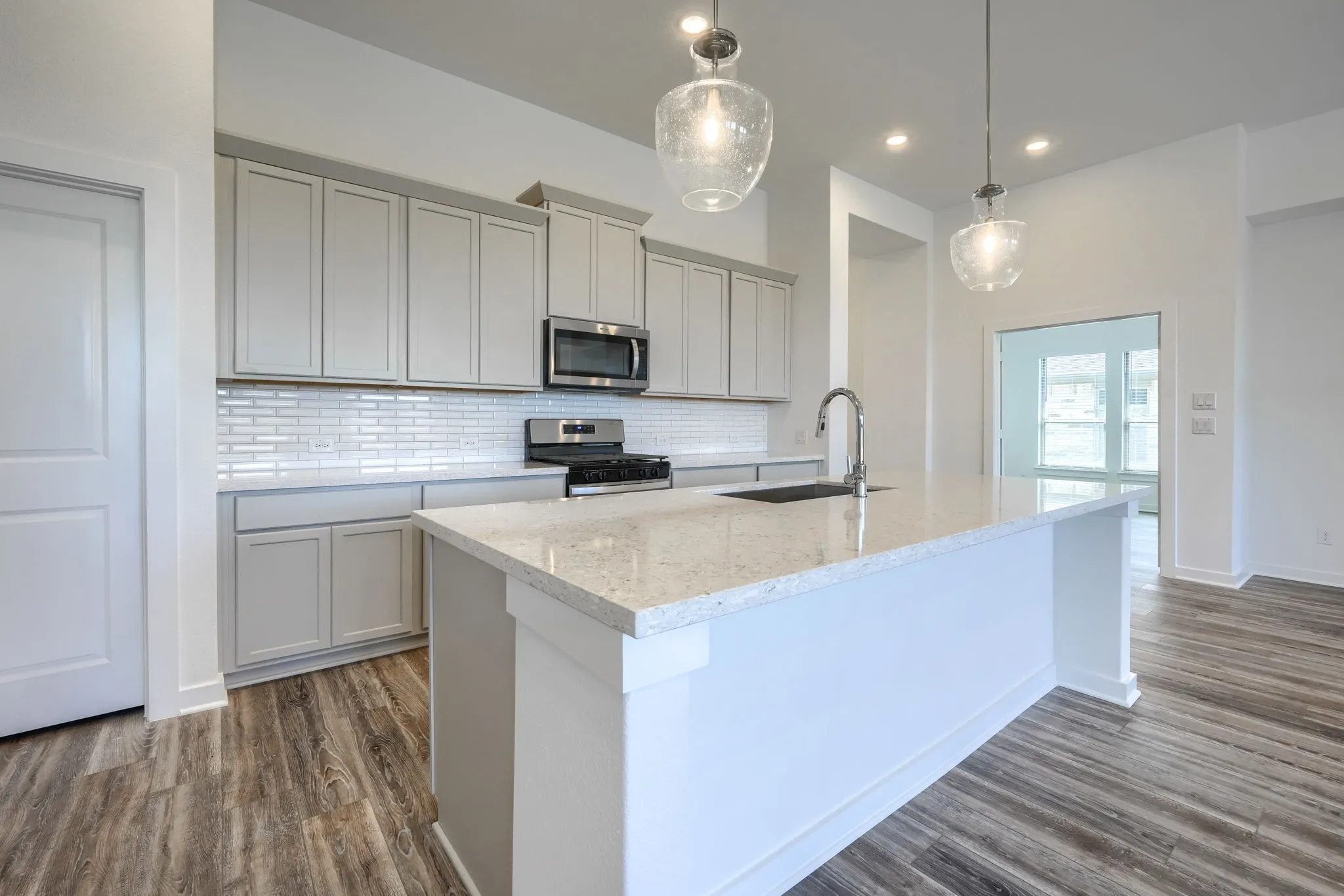Kitchen featuring a central island with a light-toned countertop, stainless steel sink, and gooseneck faucet