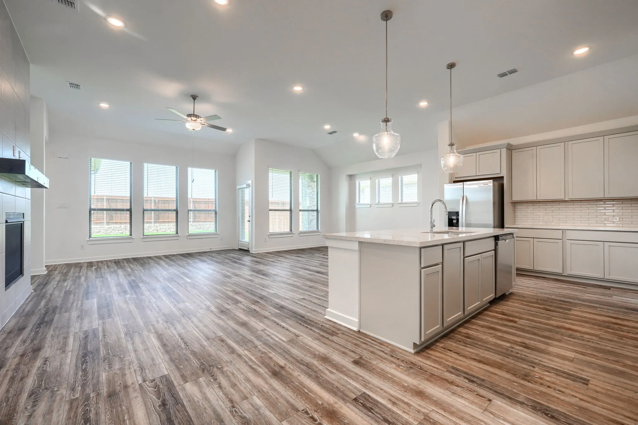Open-concept kitchen and living area featuring wood-finish flooring, recessed lighting, and a vaulted ceiling