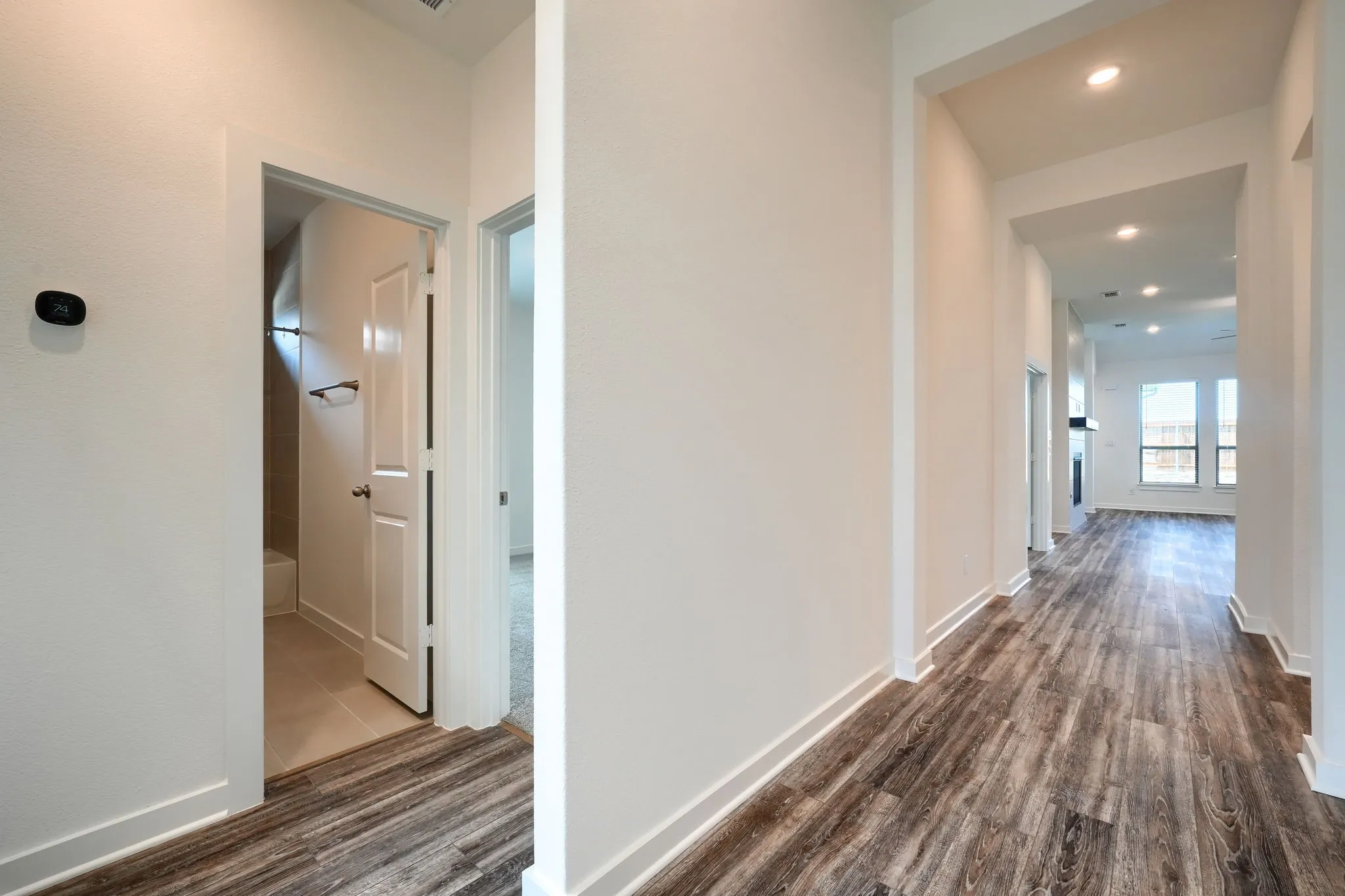 Hallway with wood-finish flooring, recessed lighting, and crisp white trim