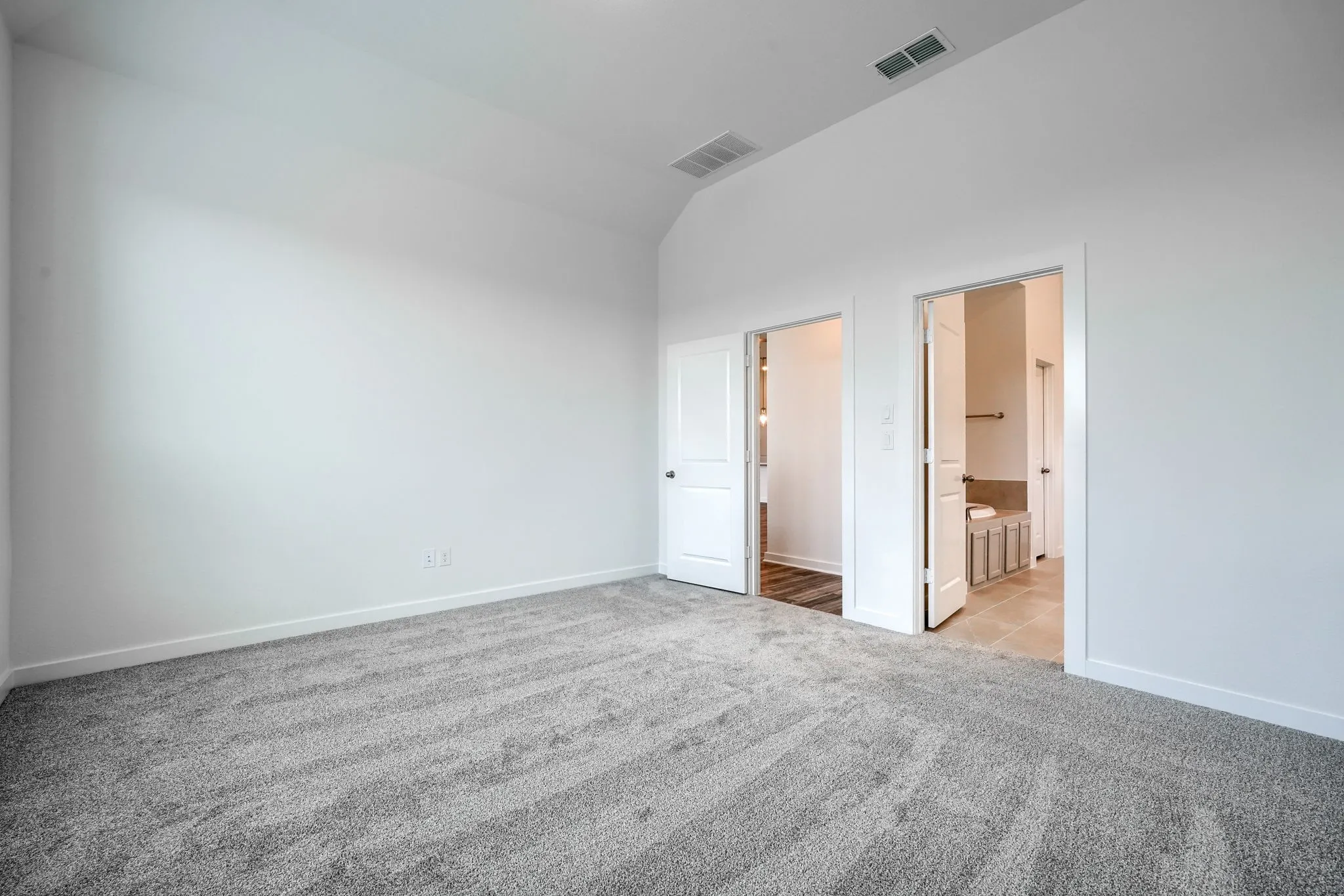 Room featuring vaulted ceiling, light gray carpet, white walls, and white trim