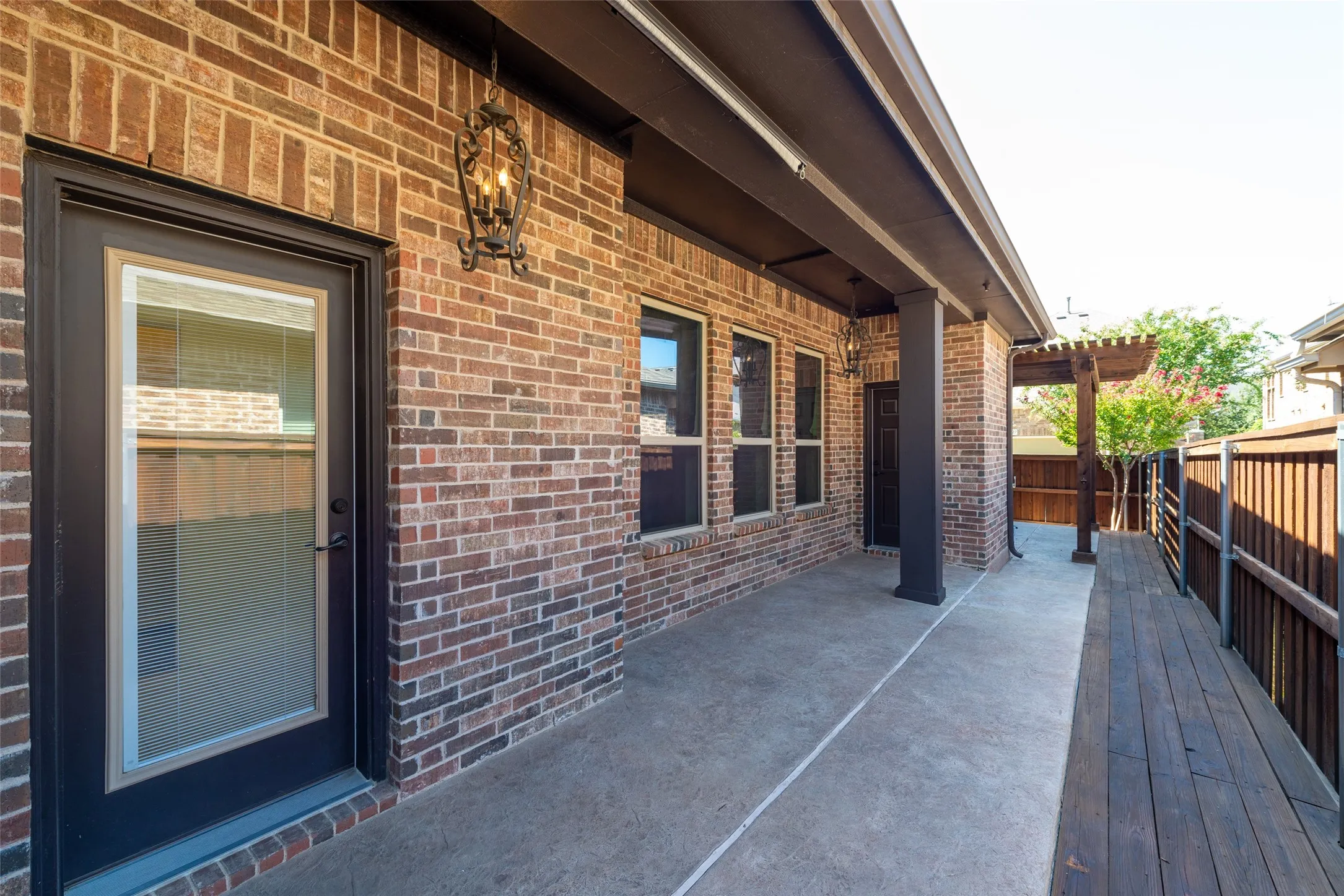 Covered patio featuring a concrete slab, red brick exterior, and dark trim