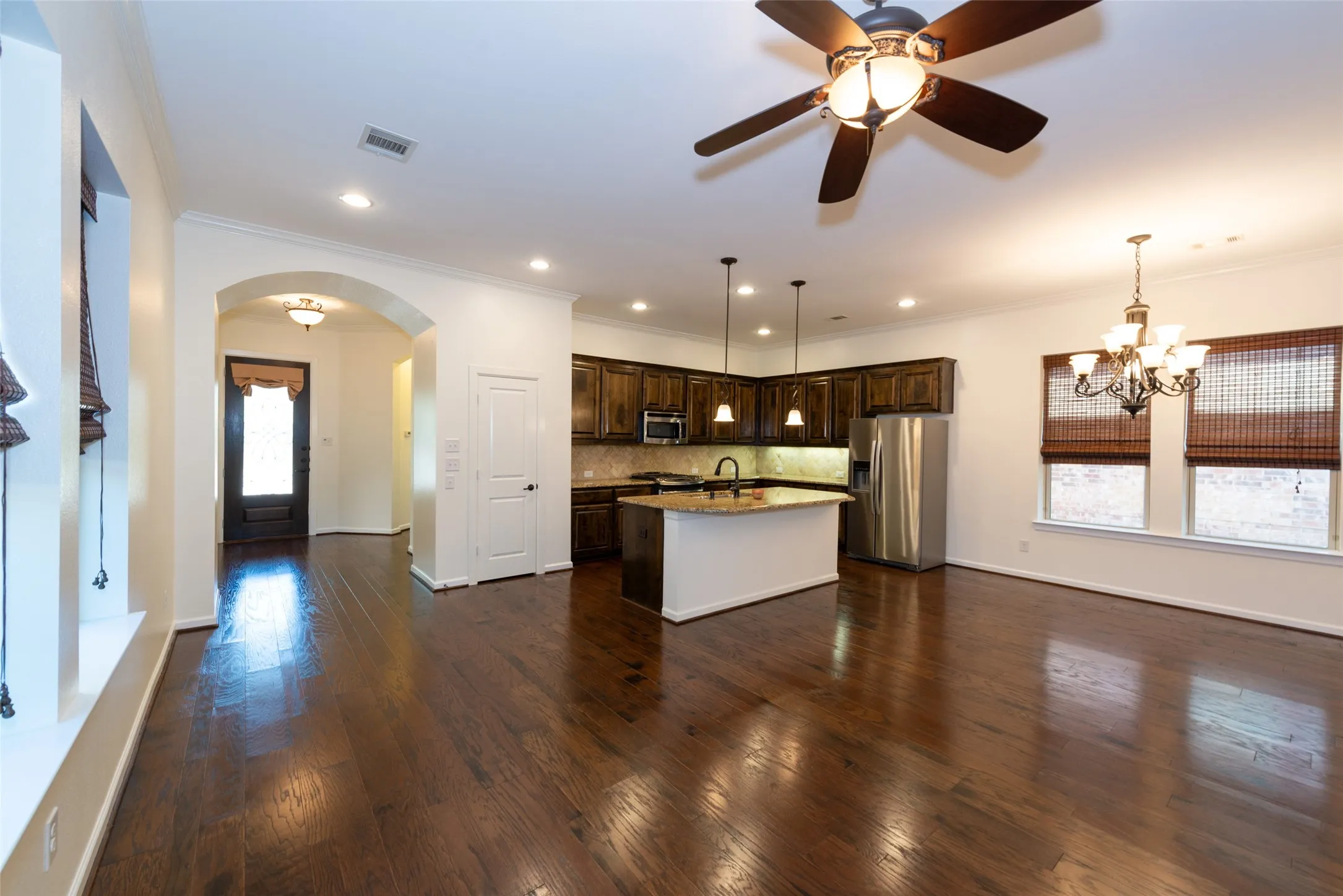 Open-concept living area featuring rich wood-finish flooring, a contemporary ceiling fan, and recessed lighting