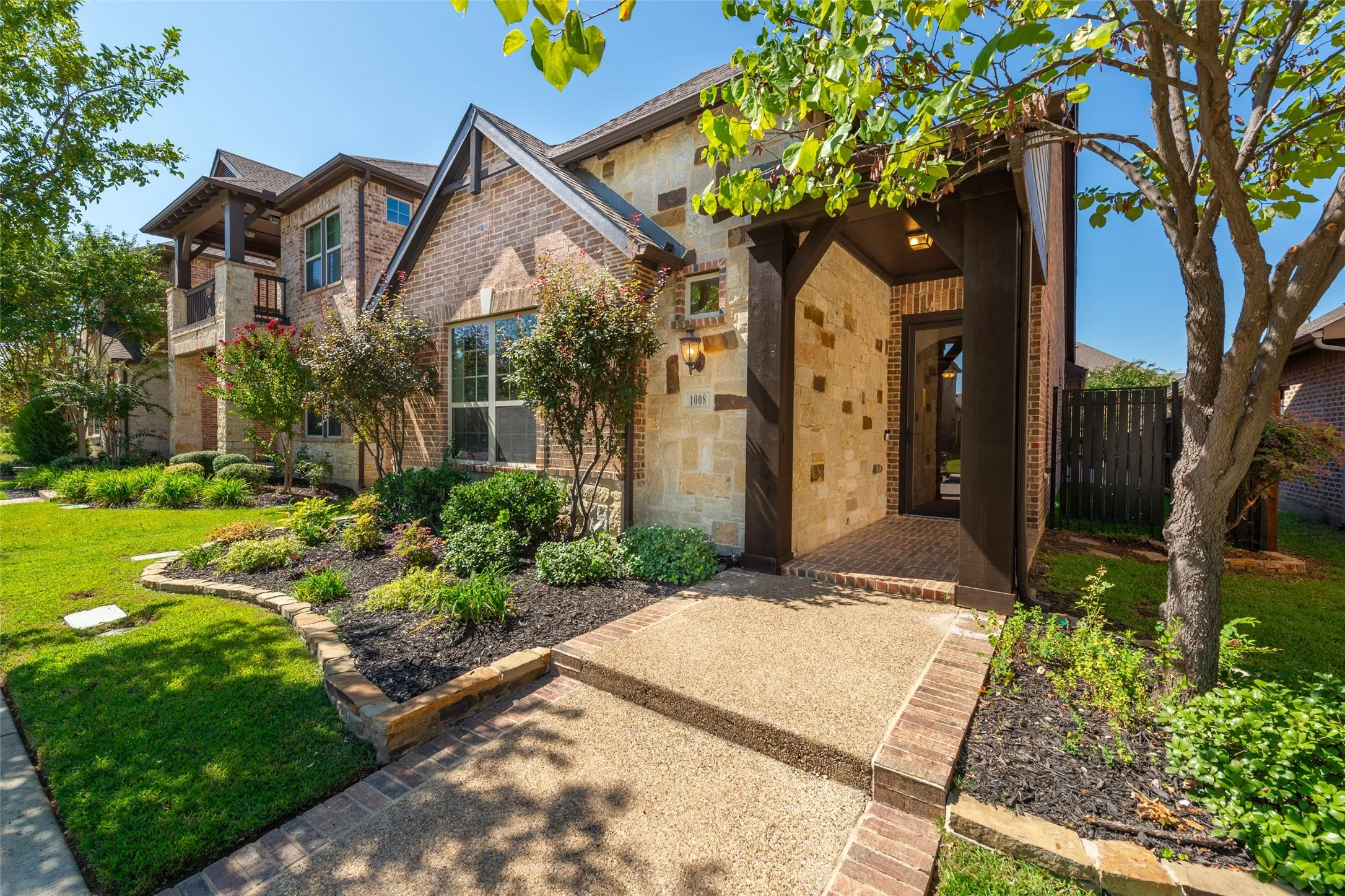 Brick and stone facade featuring an inviting covered entry with substantial wood beams