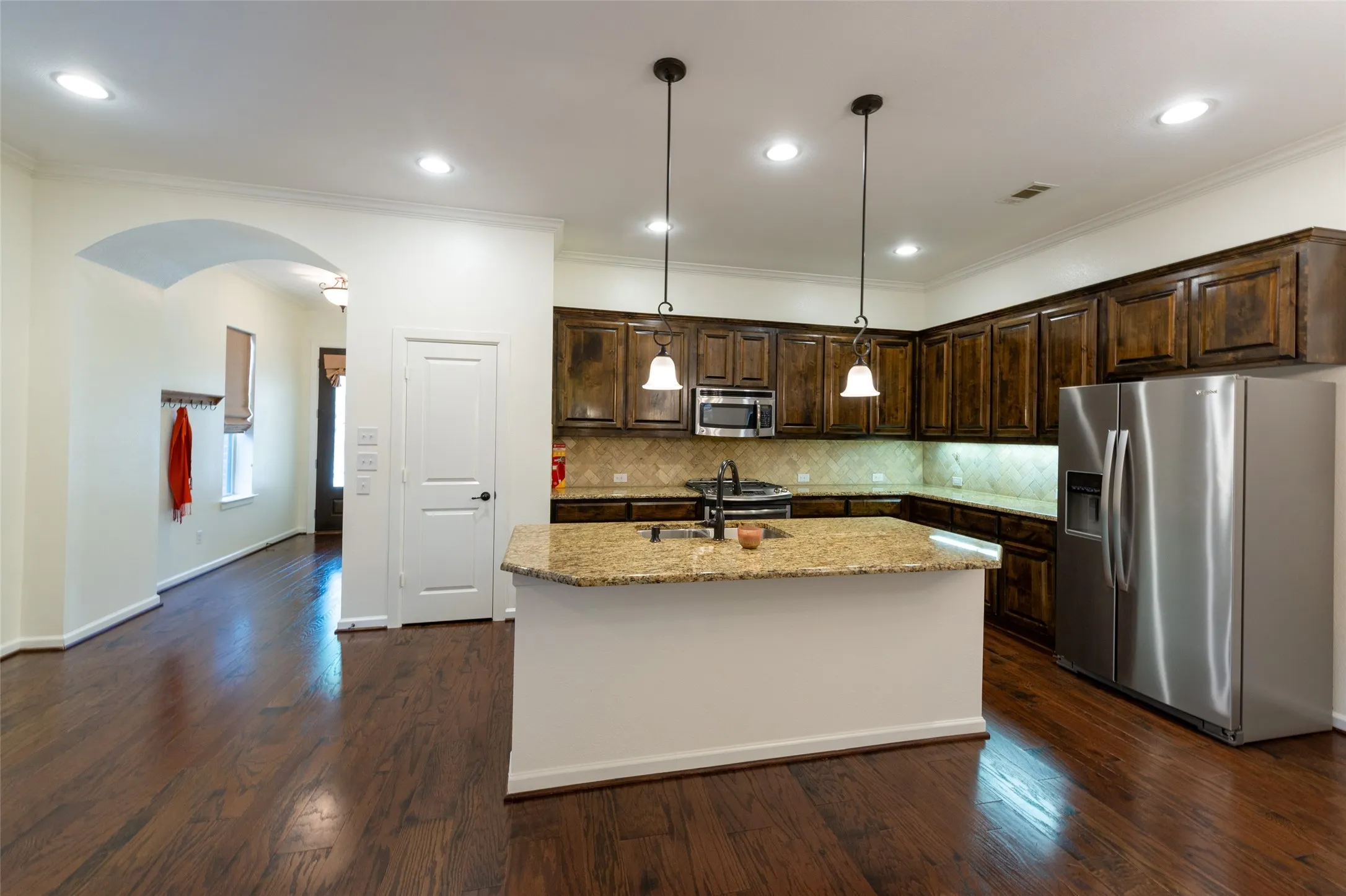 Kitchen featuring wood-finish flooring, dark wood cabinetry, granite countertops, and stainless steel appliances