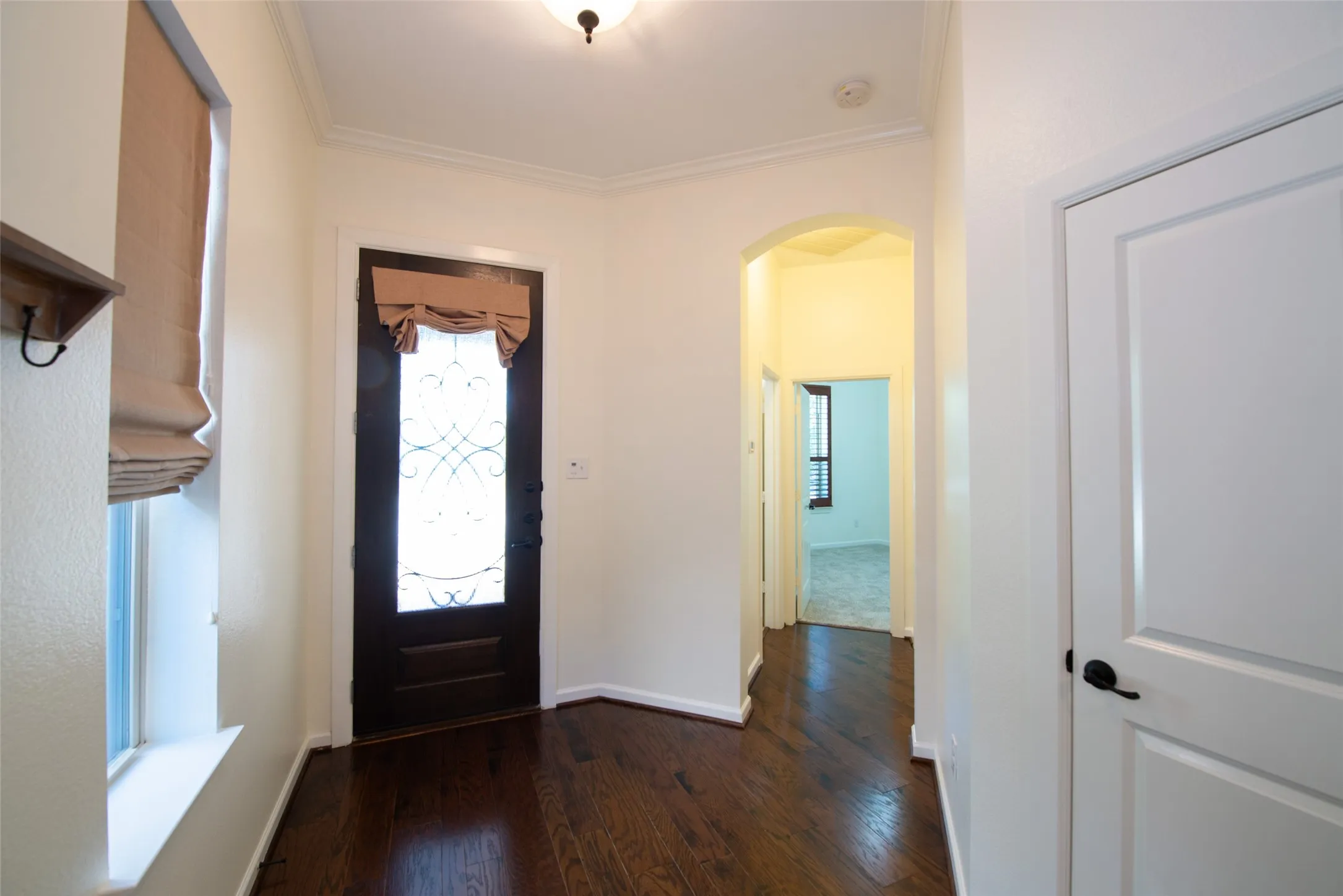 Entryway featuring dark wood-finish flooring, white baseboards, and crown molding