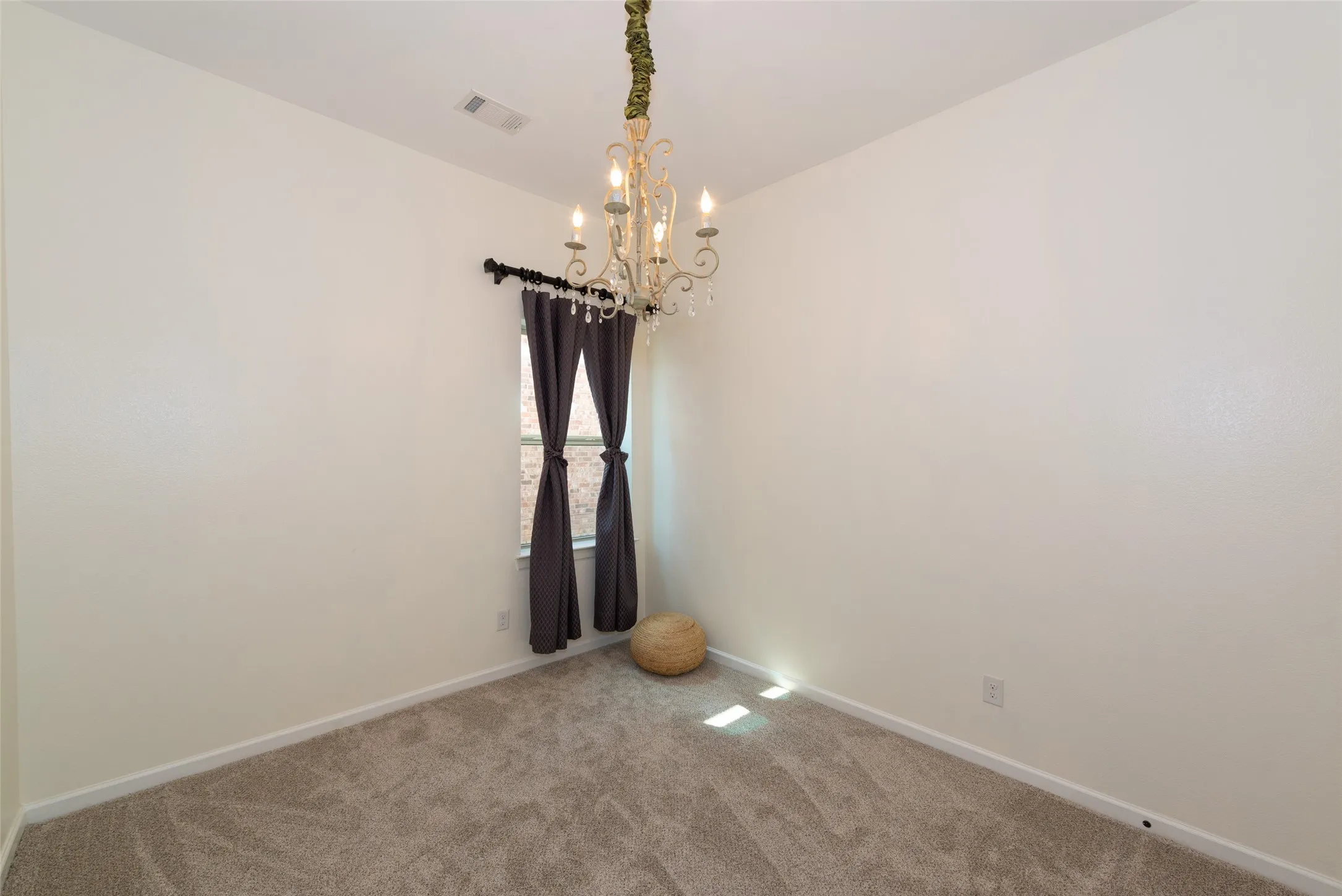 Room featuring light neutral painted walls and a single window with dark drapes