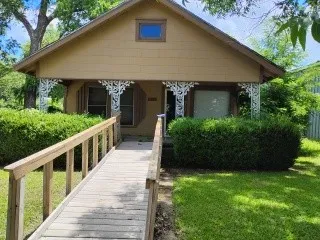 Front elevation featuring a covered porch with decorative scrollwork, an accessible ramp entrance, and an attic window