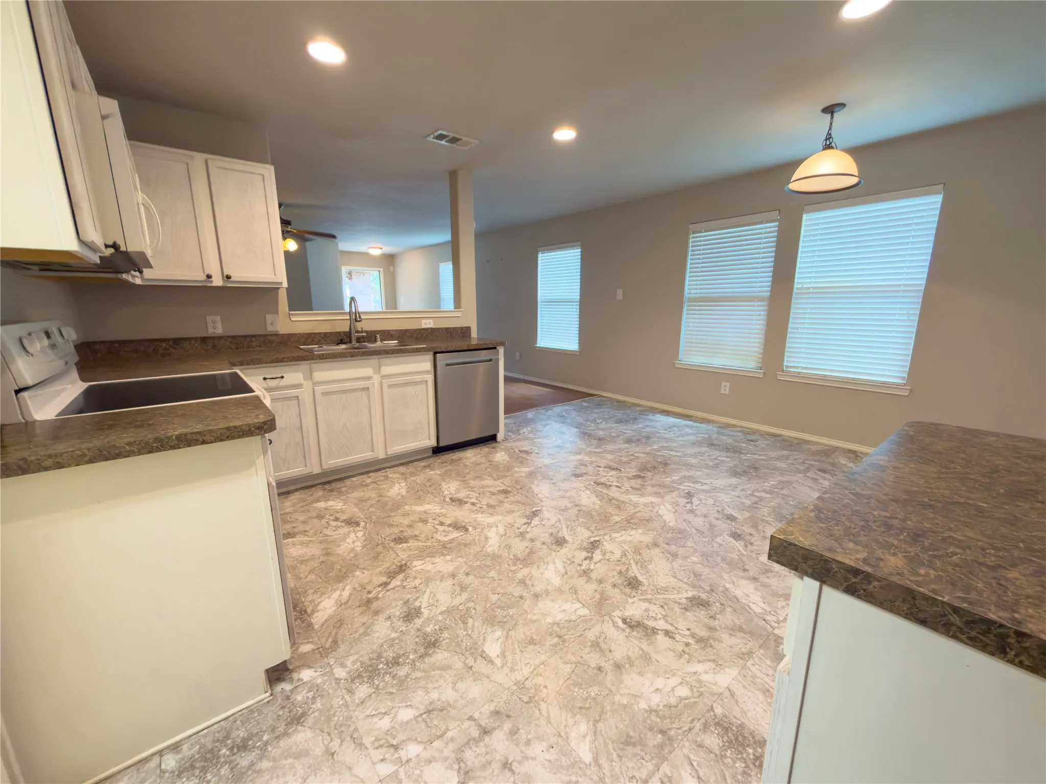 Kitchen featuring white cabinetry, dark speckled countertops, and stainless steel dishwasher