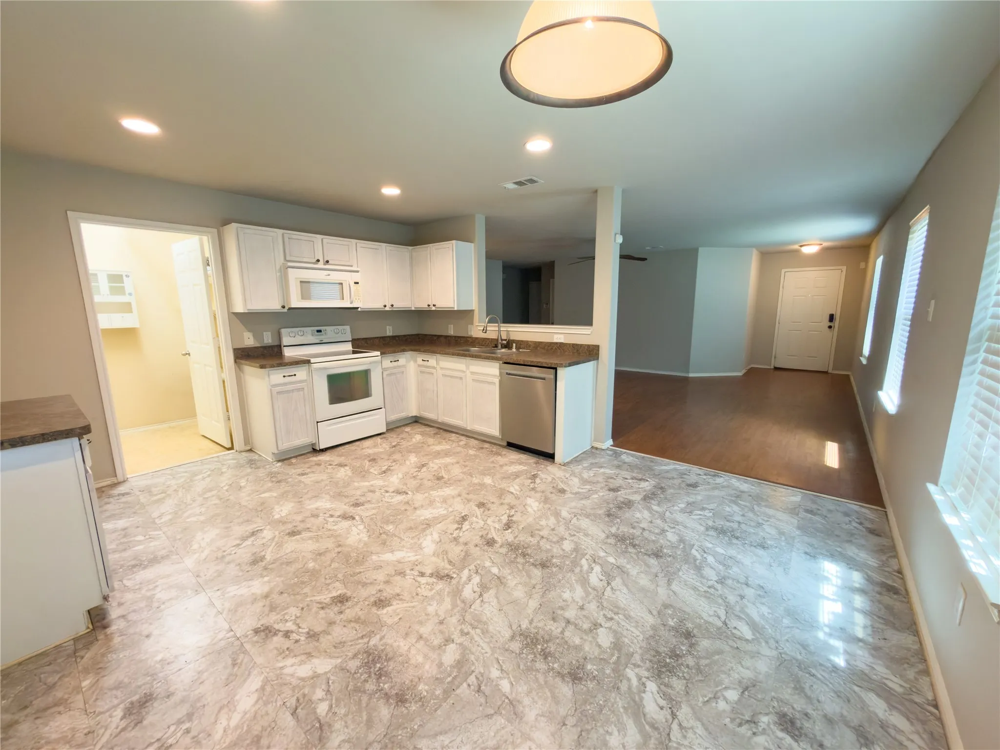 Kitchen featuring white cabinetry, dark countertops, and stainless steel dishwasher