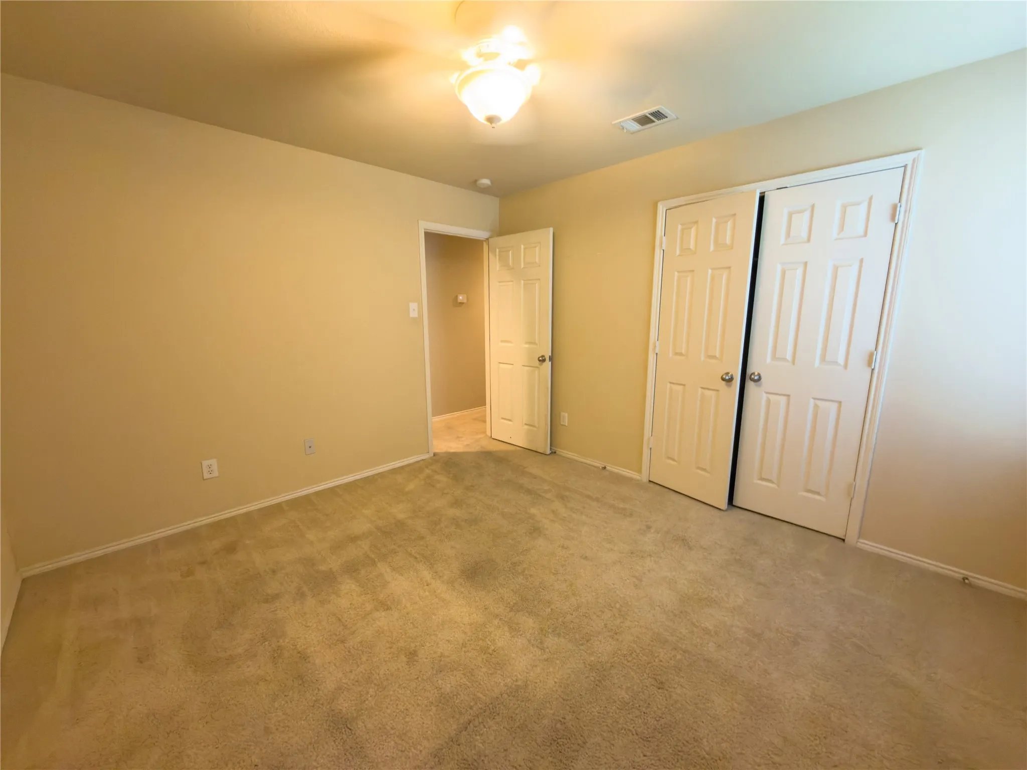 Carpeted room featuring neutral-toned walls, white baseboards, and a semi-flush mount ceiling light