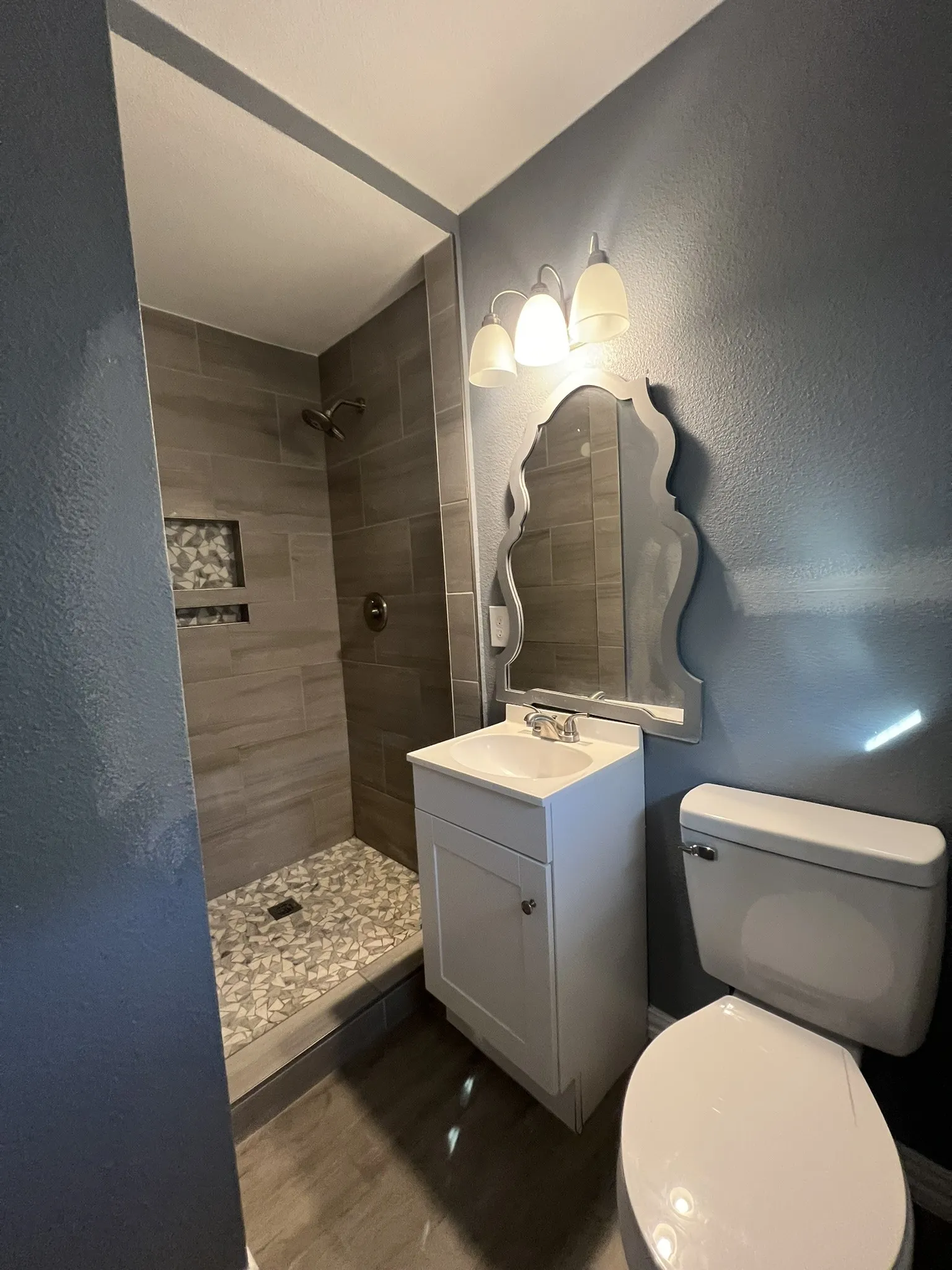 Bathroom featuring a standing shower with stone tile flooring and a recessed niche