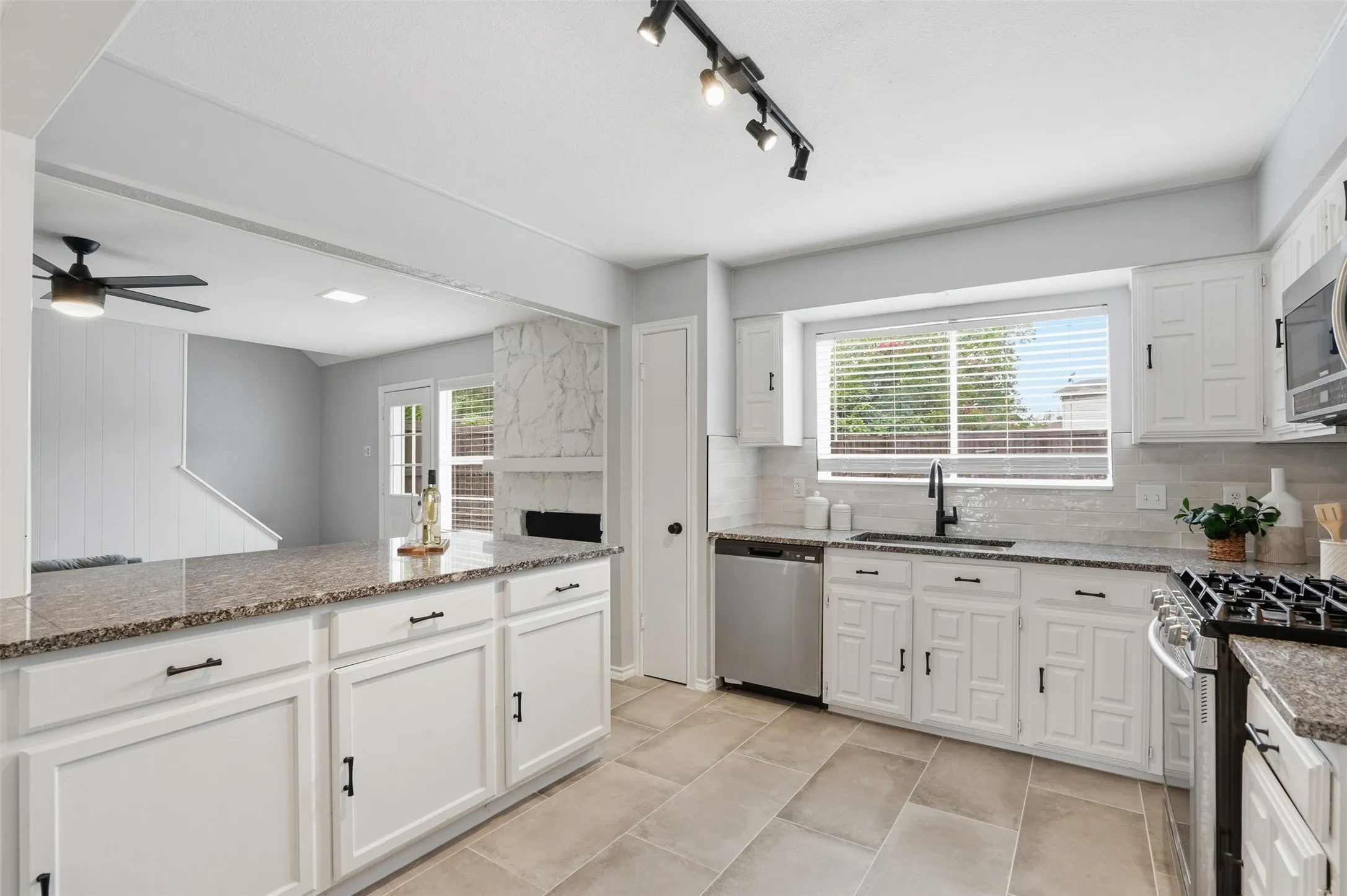 Kitchen featuring granite countertops, white cabinetry, stainless steel dishwasher, and a gas range