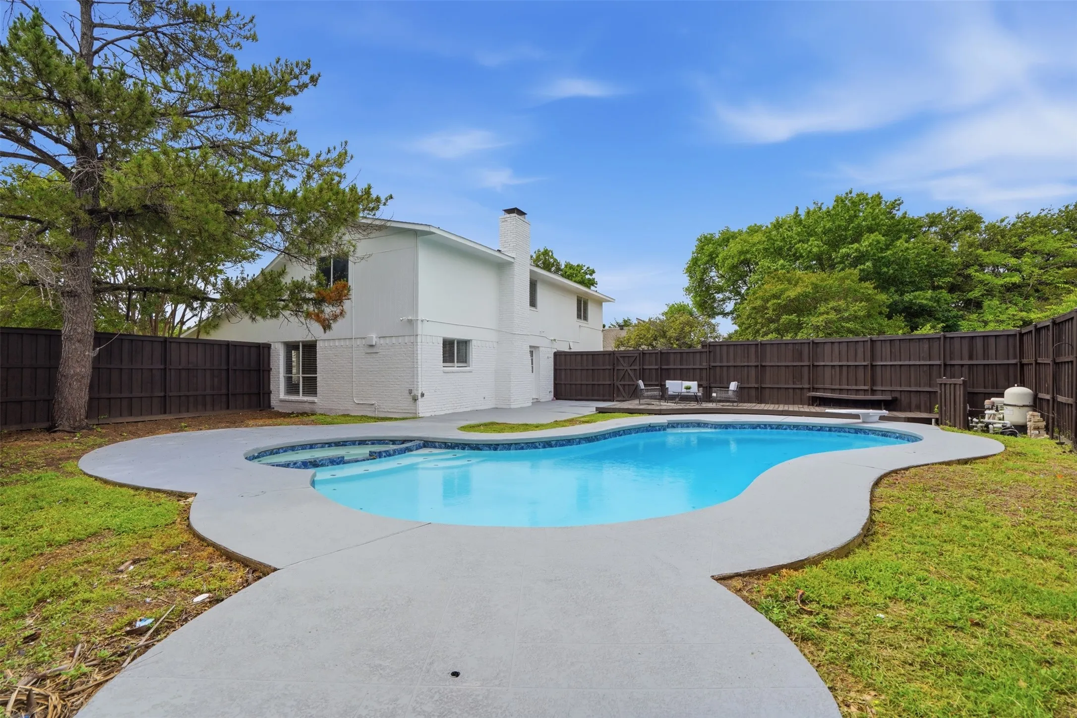 Freeform swimming pool featuring a spa, concrete coping, and surrounding patio