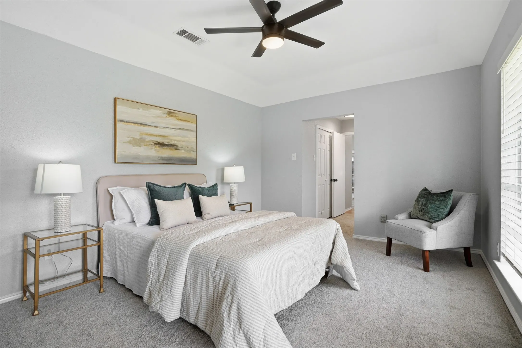 Carpeted bedroom featuring light gray walls, a ceiling fan with integrated lighting, window with blinds, and white trim throughout