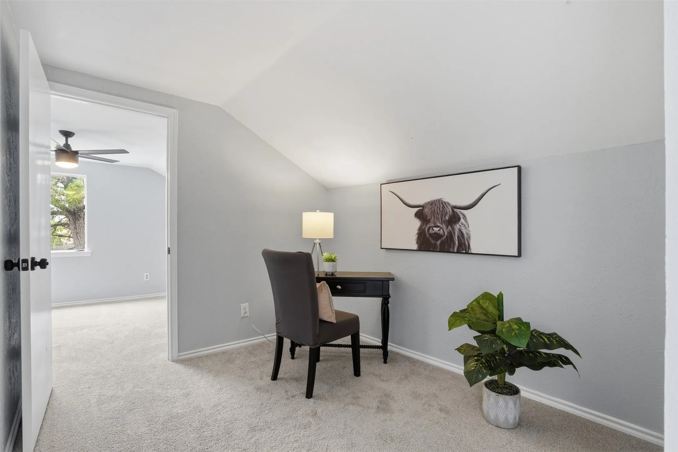 Carpeted hallway with a sloped ceiling leading to an open doorway