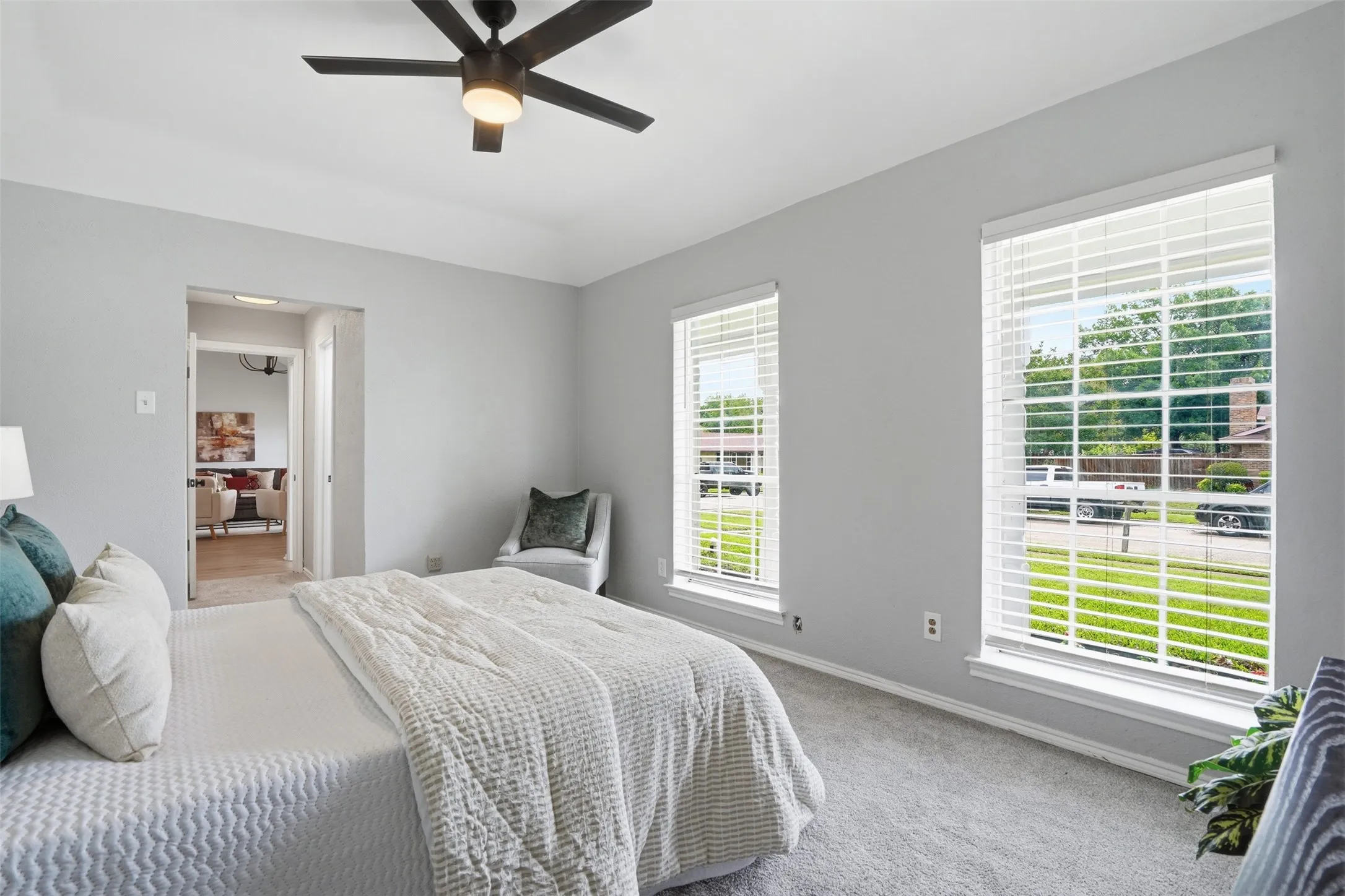 Carpeted room with a modern ceiling fan and two windows featuring white blinds