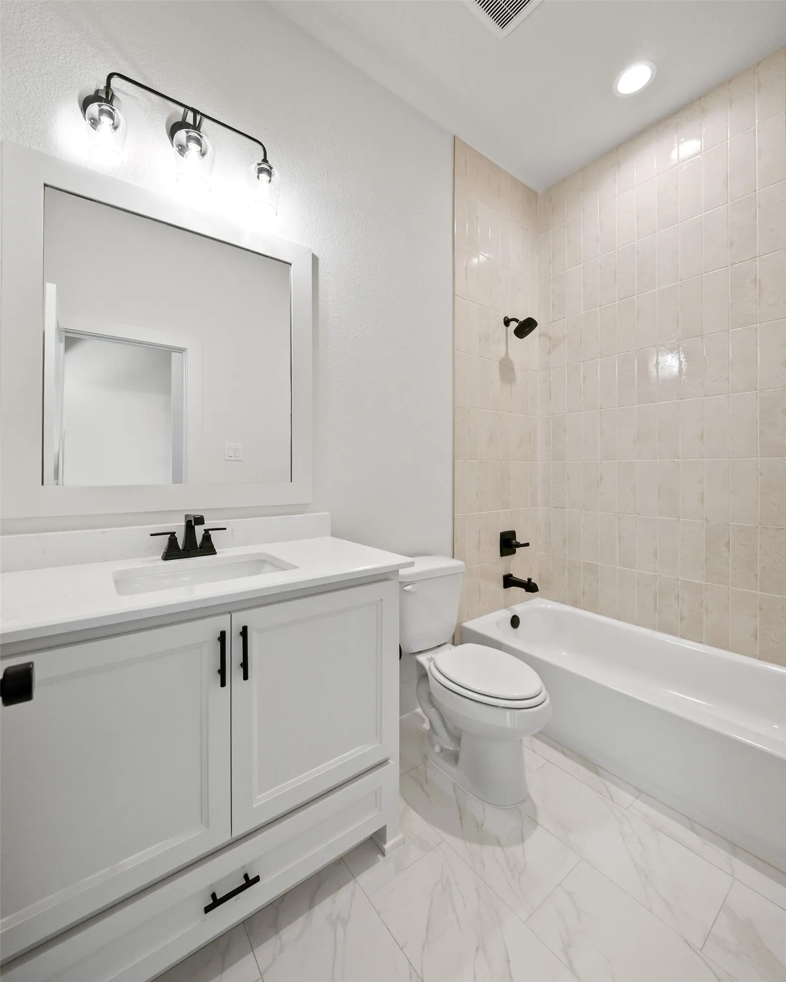Contemporary bathroom featuring a white vanity with a rectangular undermount sink, quartz countertop, and black hardware