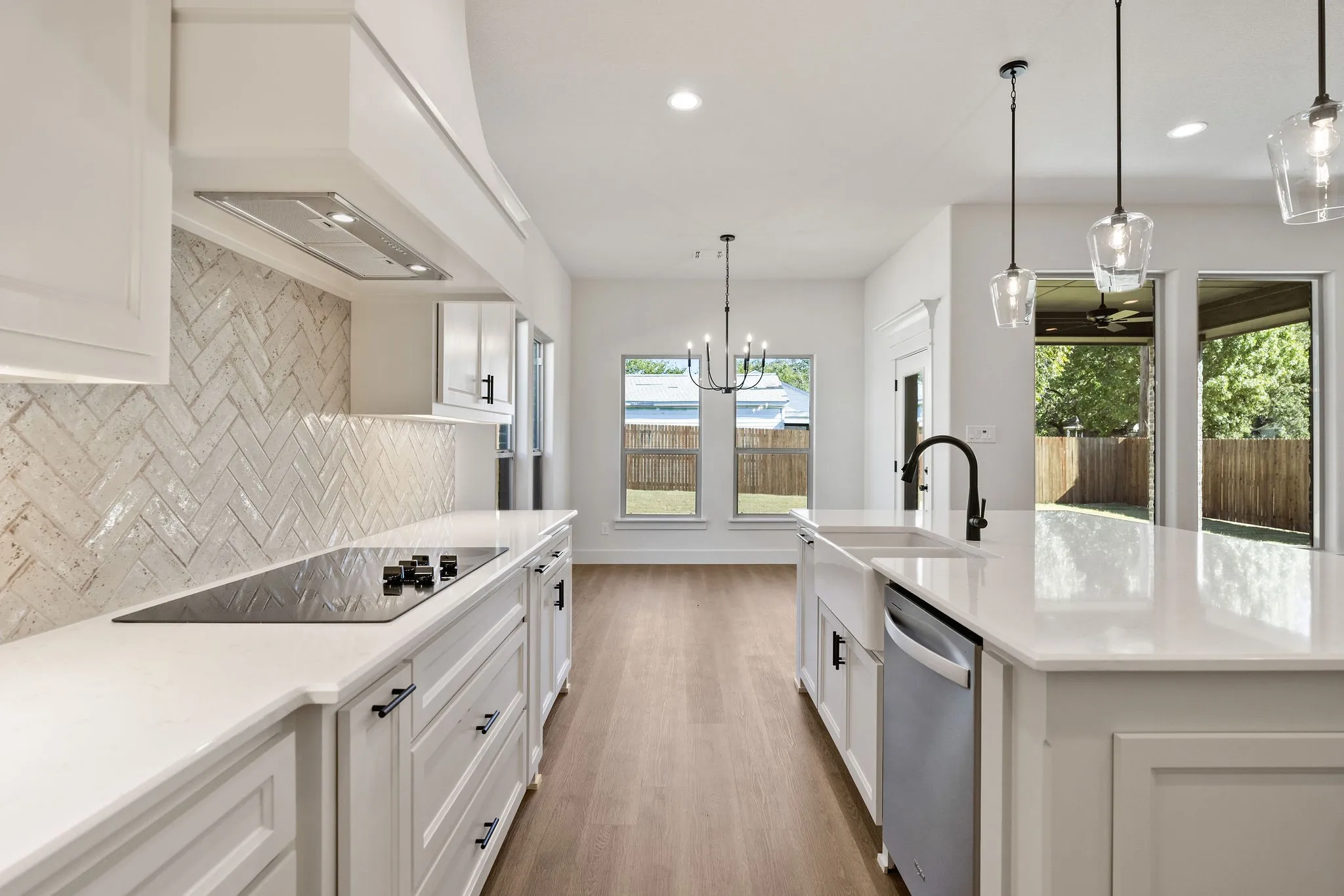 Modern kitchen featuring a large island with a farmhouse sink, stainless steel dishwasher, and pendant lighting