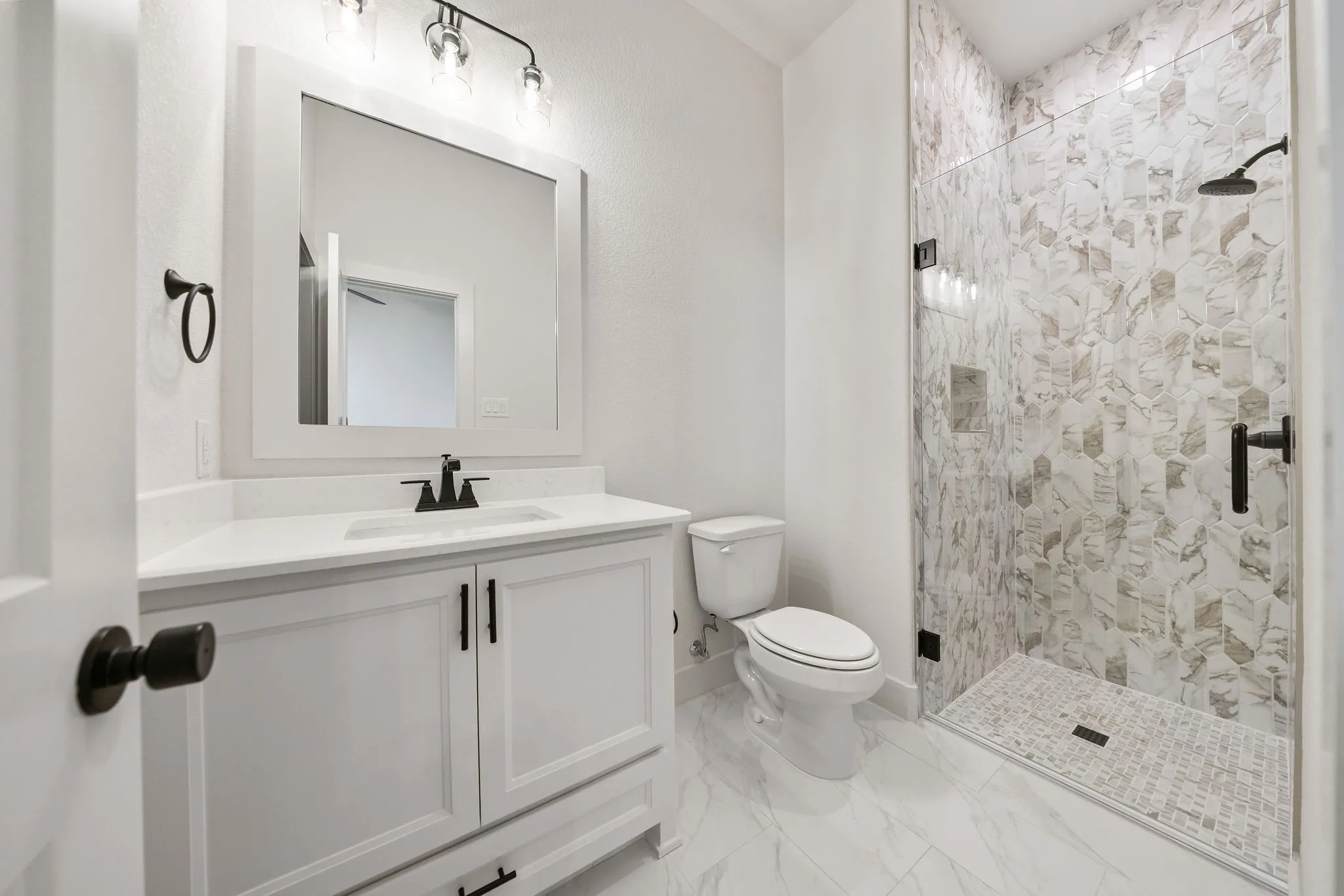Contemporary bathroom featuring a frameless glass shower enclosure with patterned tile surround and a tiled shower pan