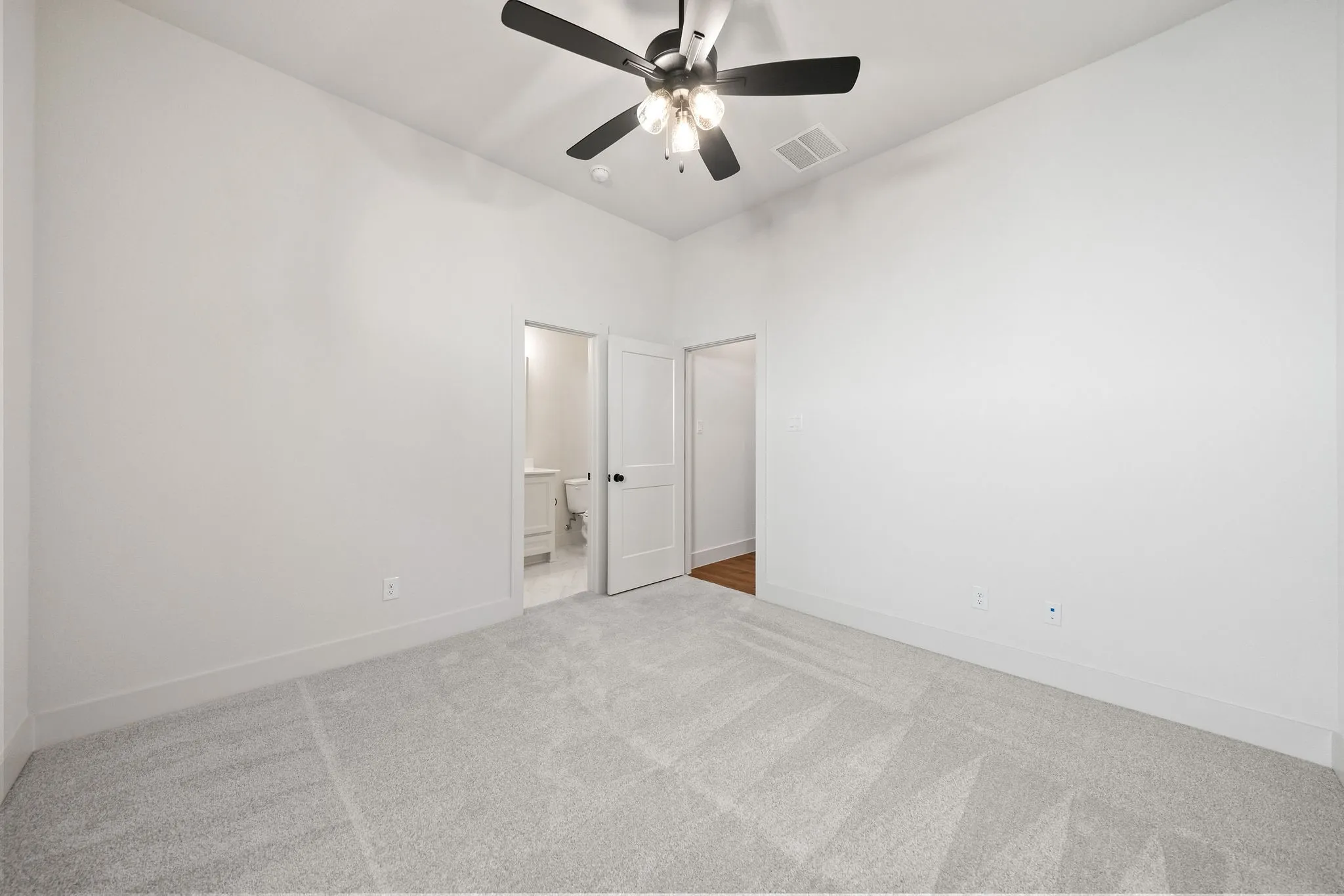 Carpeted interior space with a ceiling fan light fixture, flat white walls, and white trim