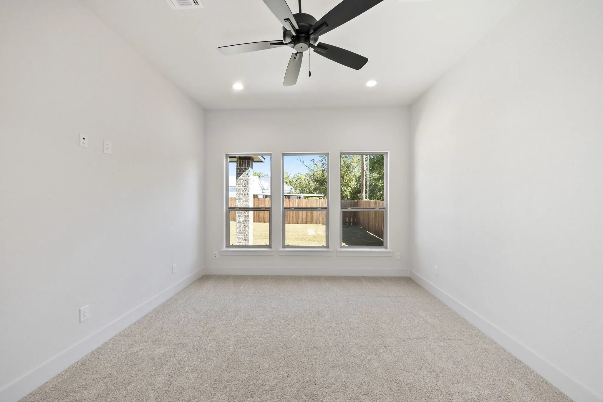 Bright room featuring a ceiling fan with integrated lighting, three large windows, recessed lighting, and carpet flooring