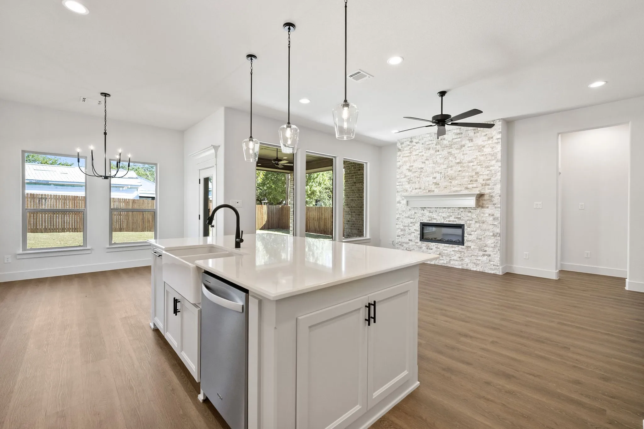 Kitchen island featuring a farmhouse sink, stainless steel dishwasher, and quartz countertop