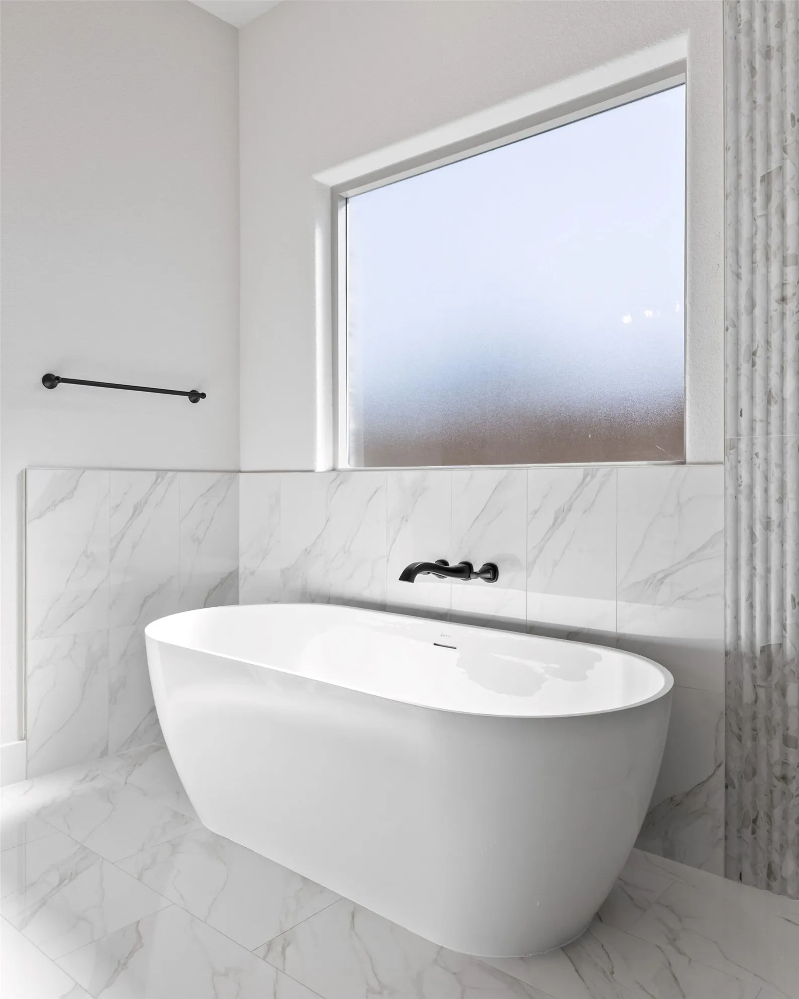 Freestanding soaking tub with a wall-mounted matte black faucet