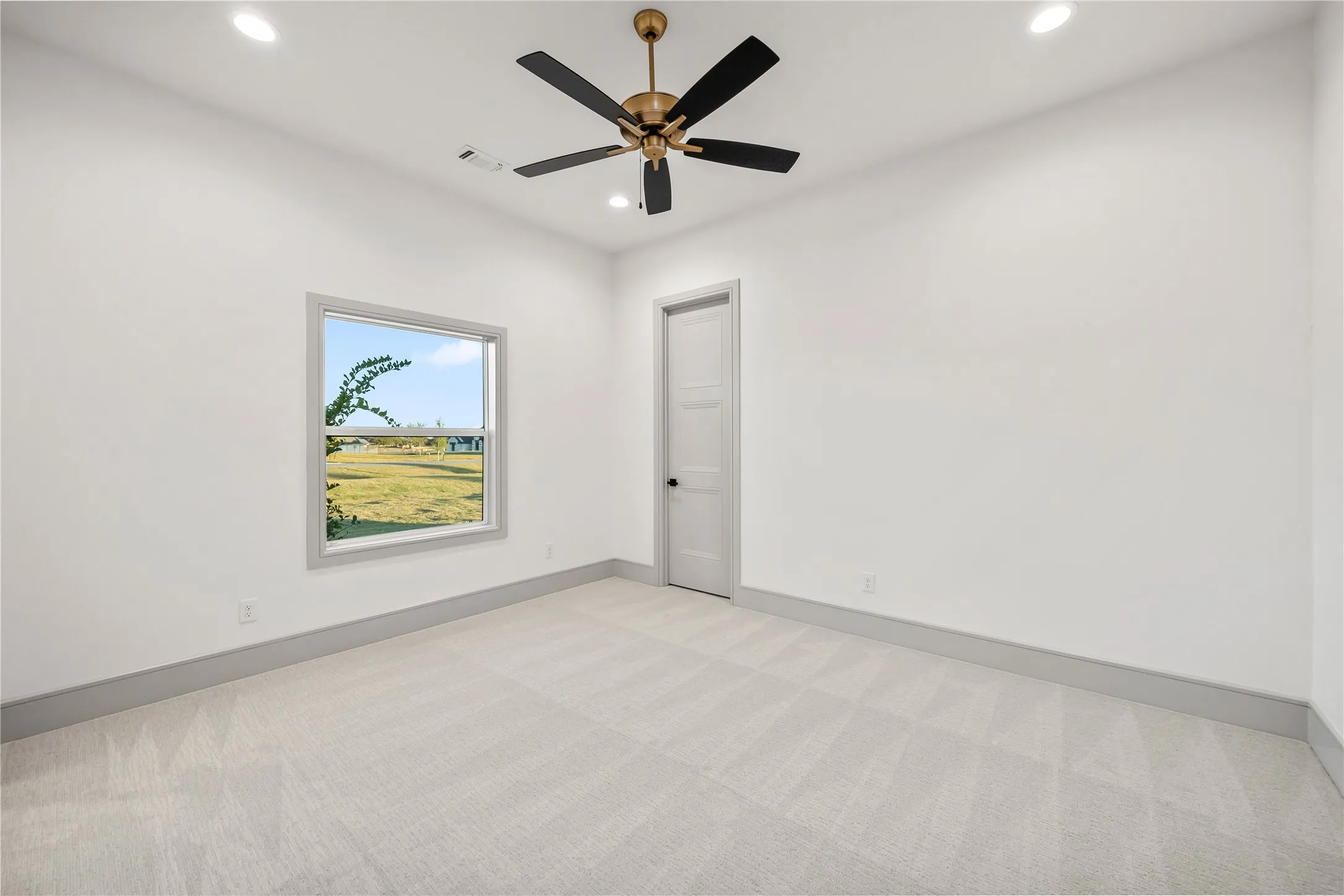 Bright interior space featuring a ceiling fan with bronze hardware, recessed lighting, and light-toned carpeting