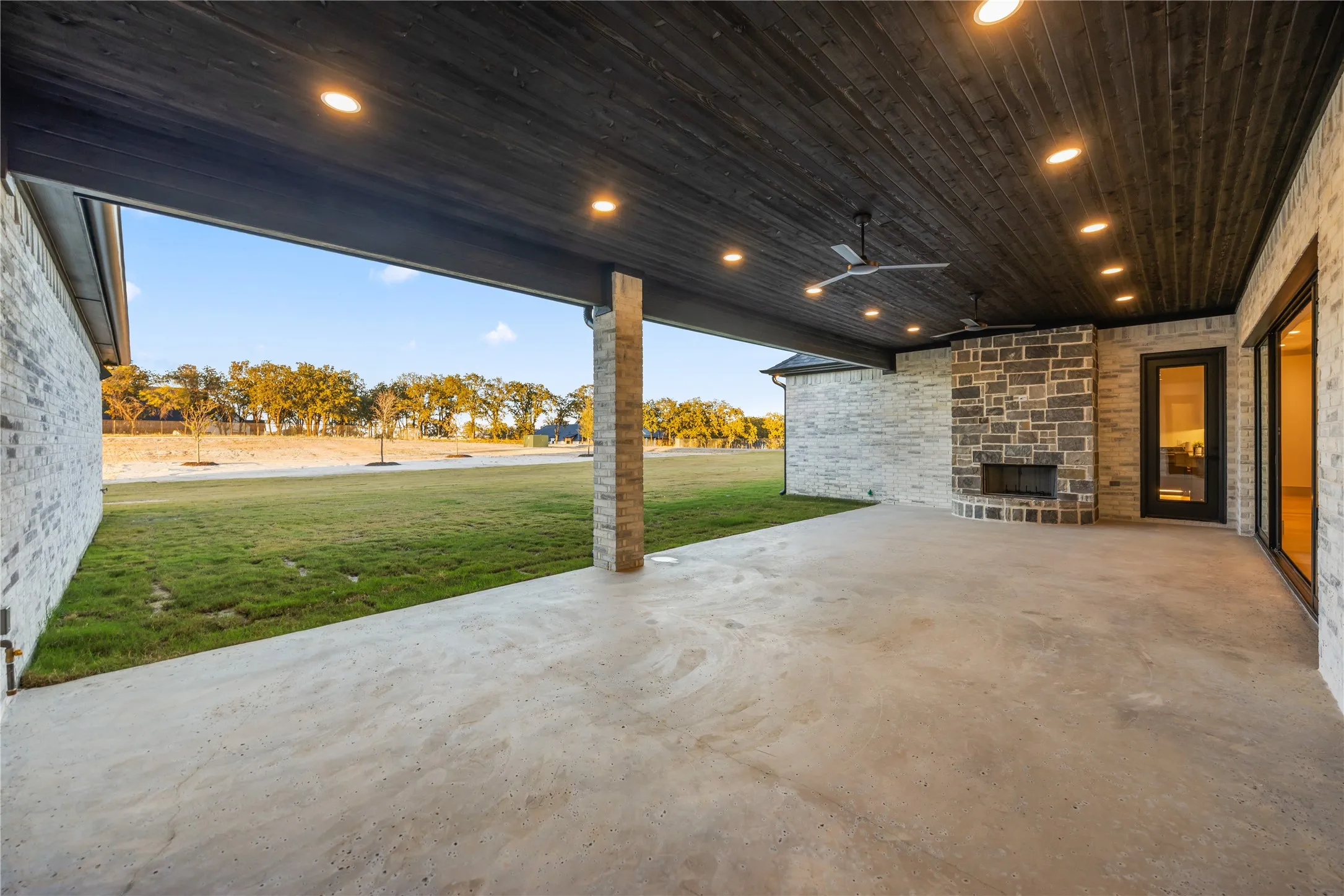 Covered outdoor living space featuring a dark wood-finish ceiling with recessed lighting and ceiling fans