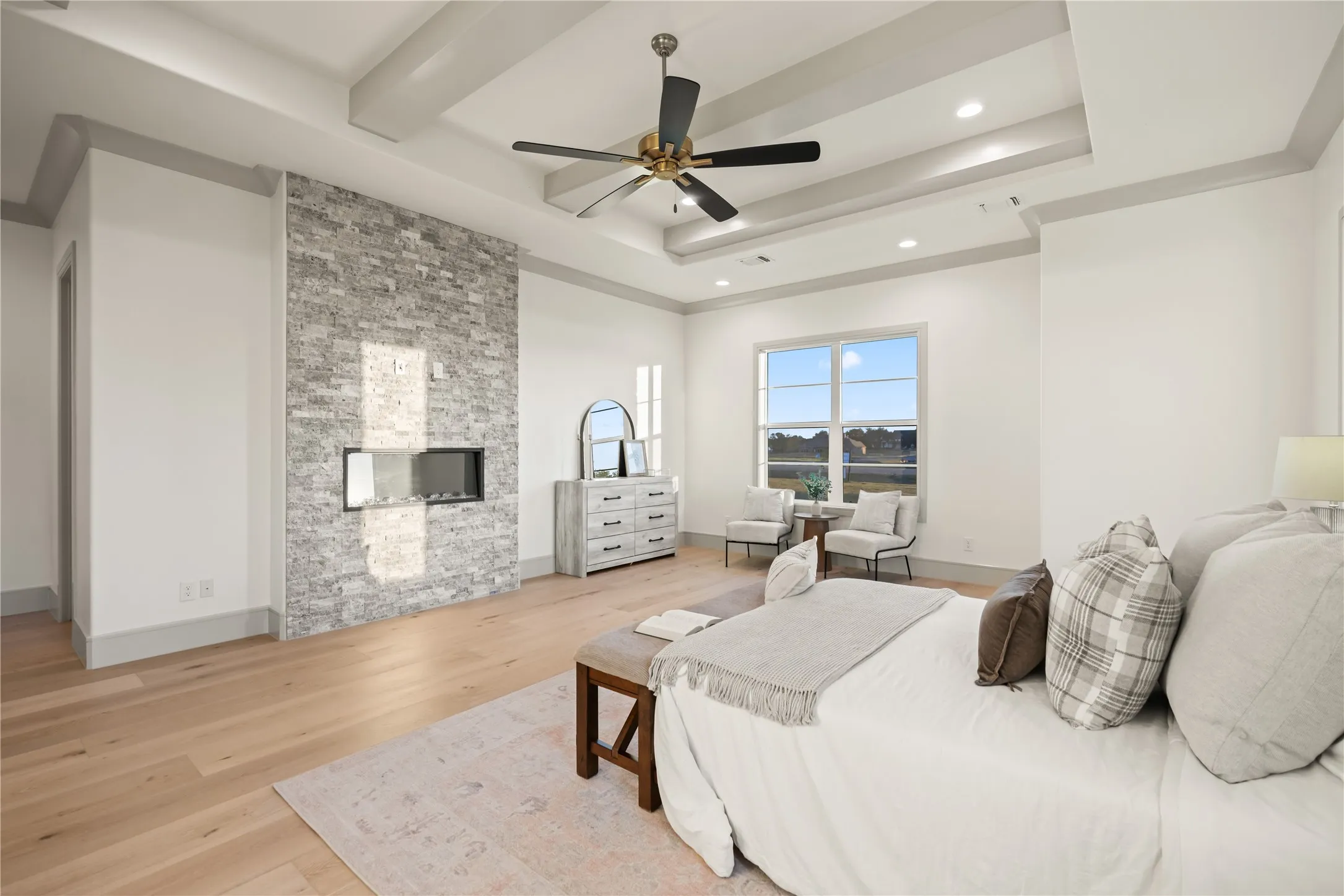 Expansive room featuring light wood-finish flooring and a tray ceiling with recessed lighting